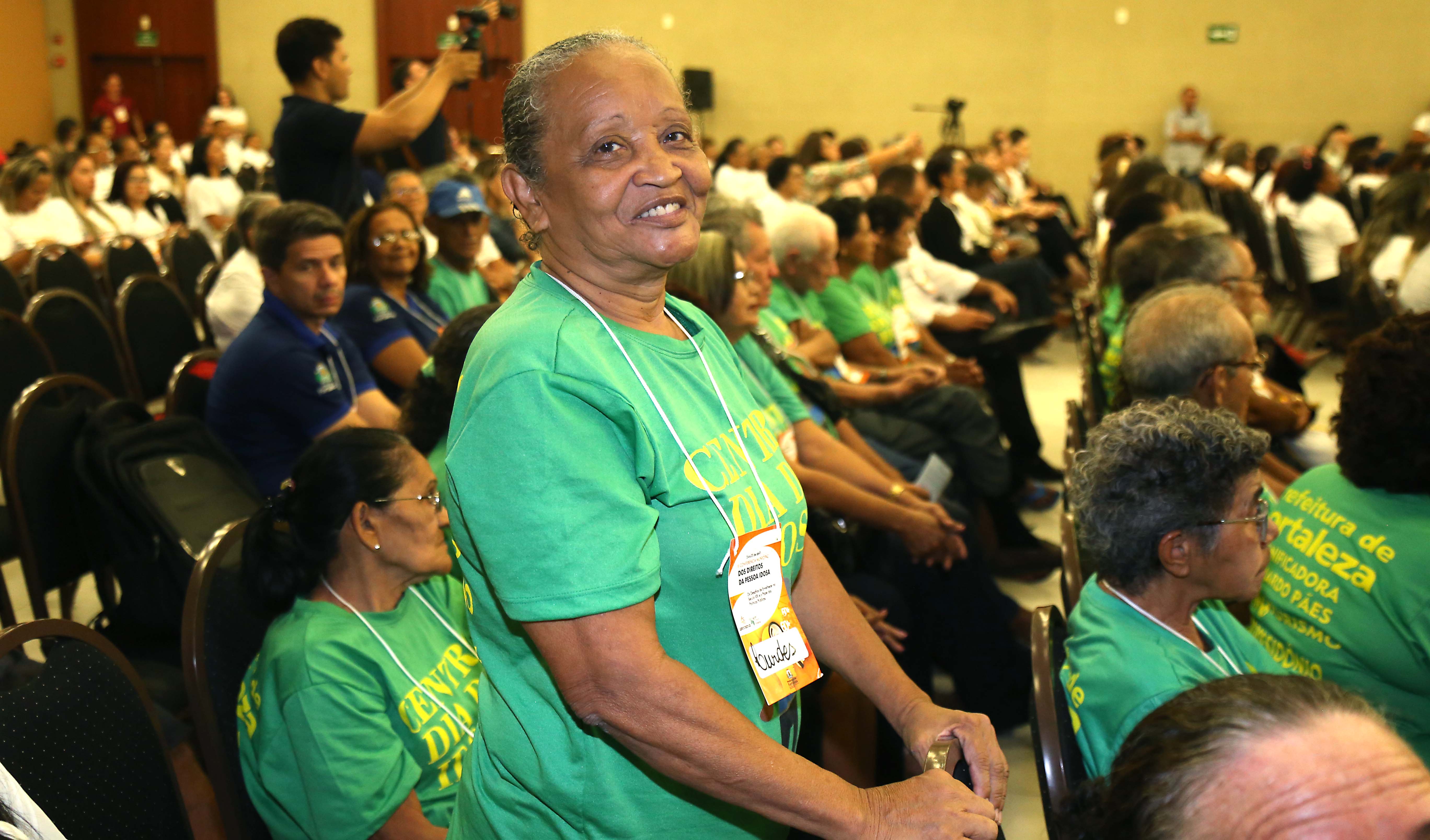 A aposentada Lourdes Alves posa para foto. Ela está em pé e usa uma blusa verde