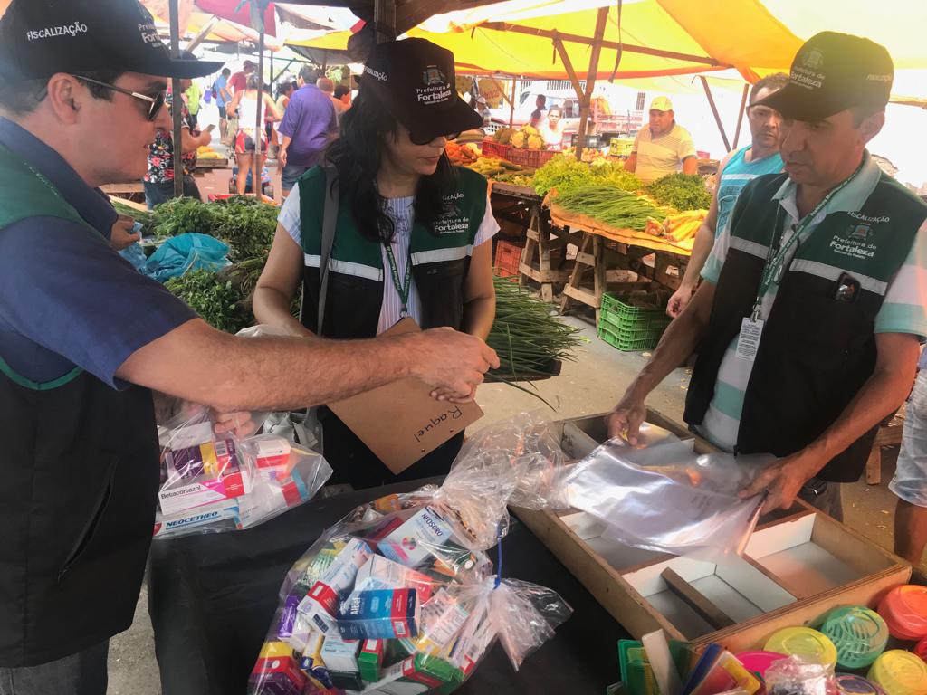 Fiscais realizando a apreensão de medicamentos vendidos em feira de rua