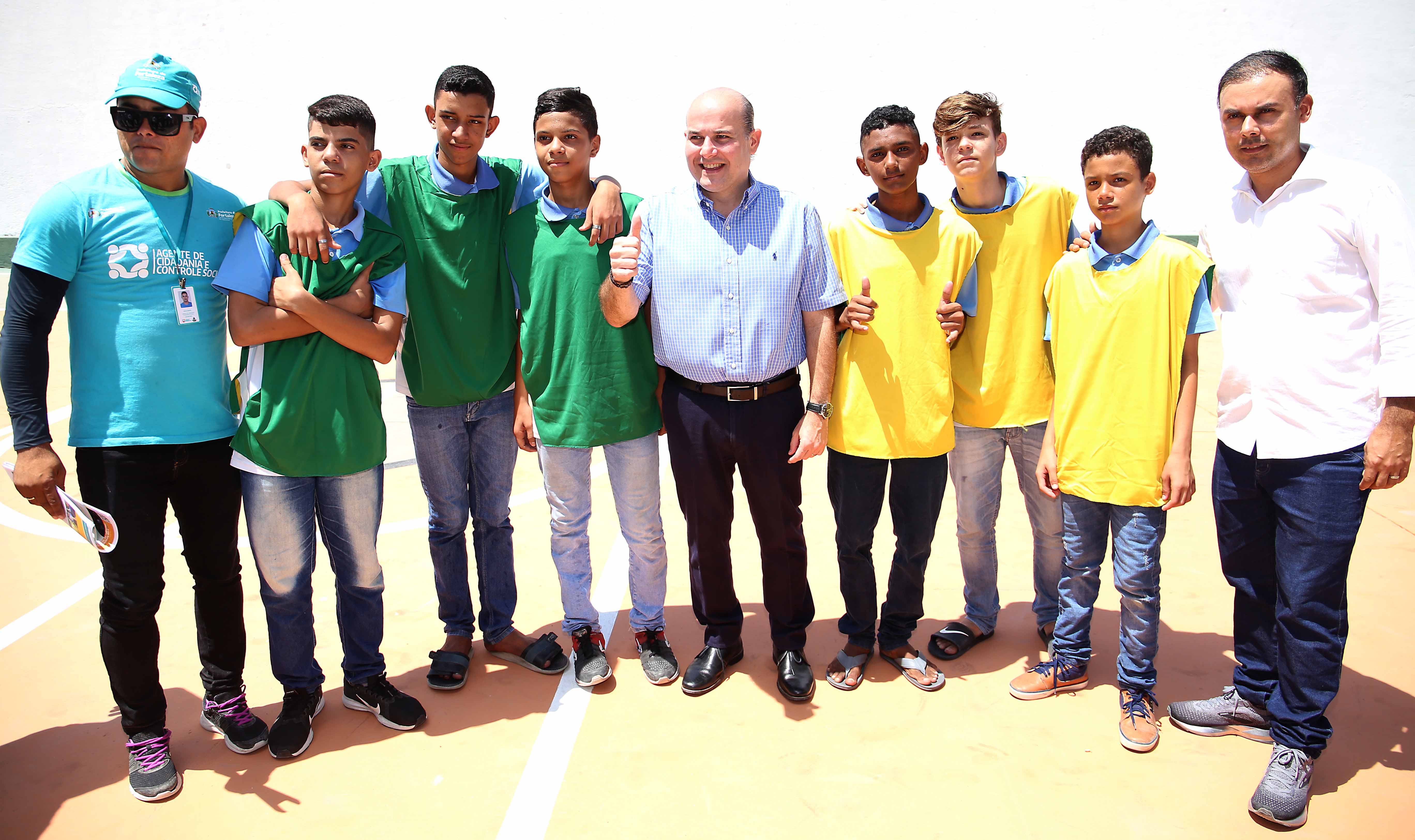 prefeito e secretário em pé ao lado de garotos com coletes de futebol posando para a foto
