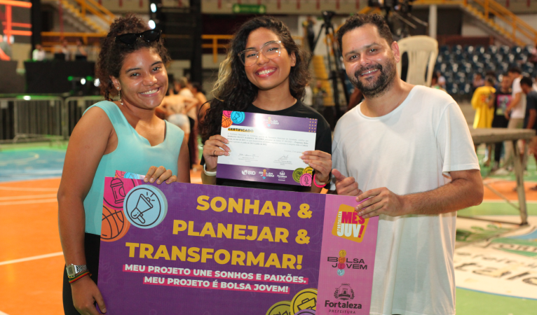 Na imagem, duas beneficiadas pelo programa Bolsa Jovem seguram seus certificados de conclusão ao lado do secretário da Juventude, Davi Gomes 