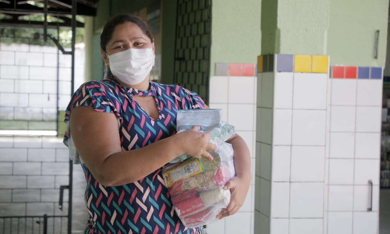 Mãe de aluno da Rede recebendo seu kit alimentação, ovos e máscaras