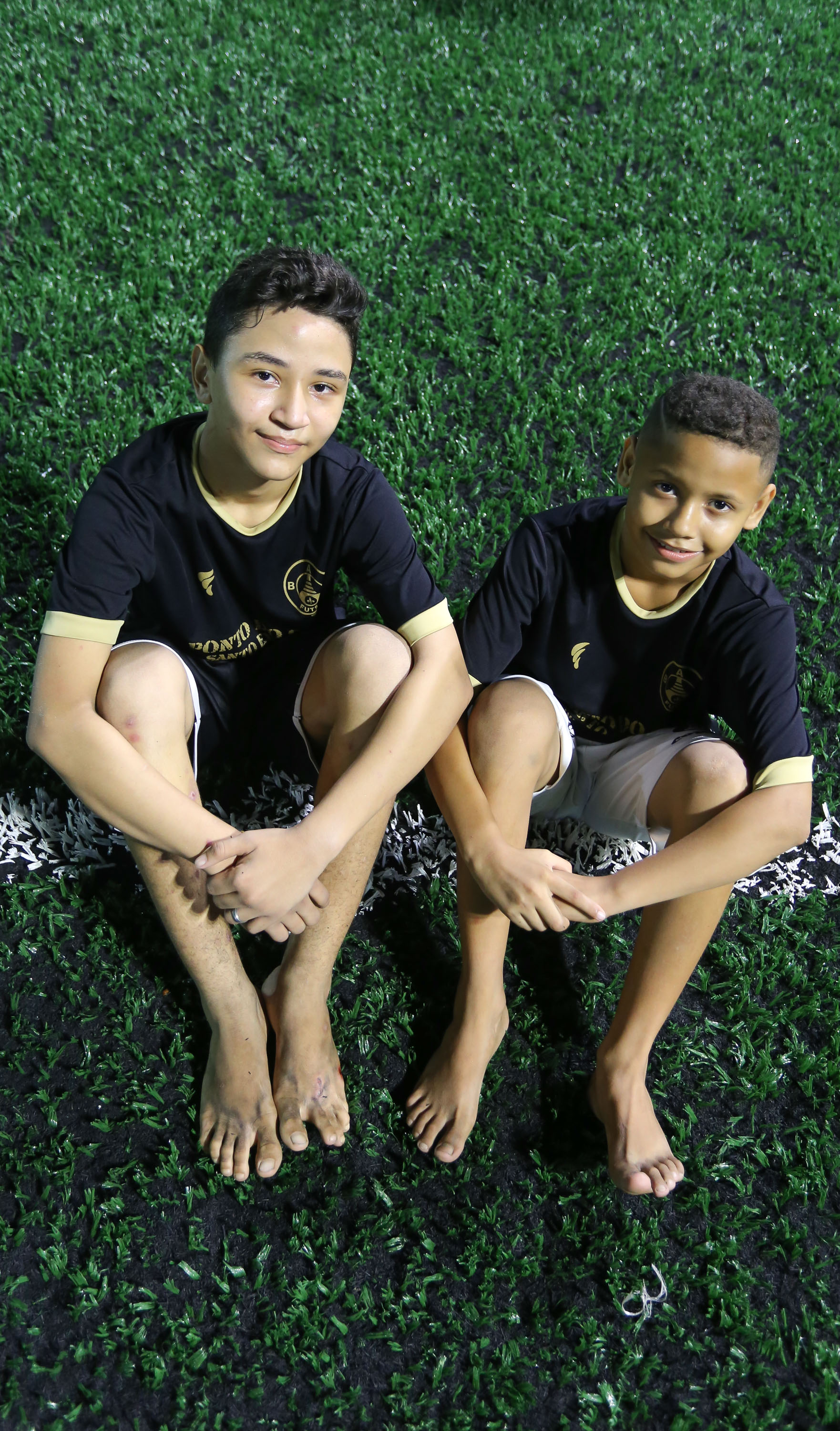dois meninos sentados num gramado, posando para a foto