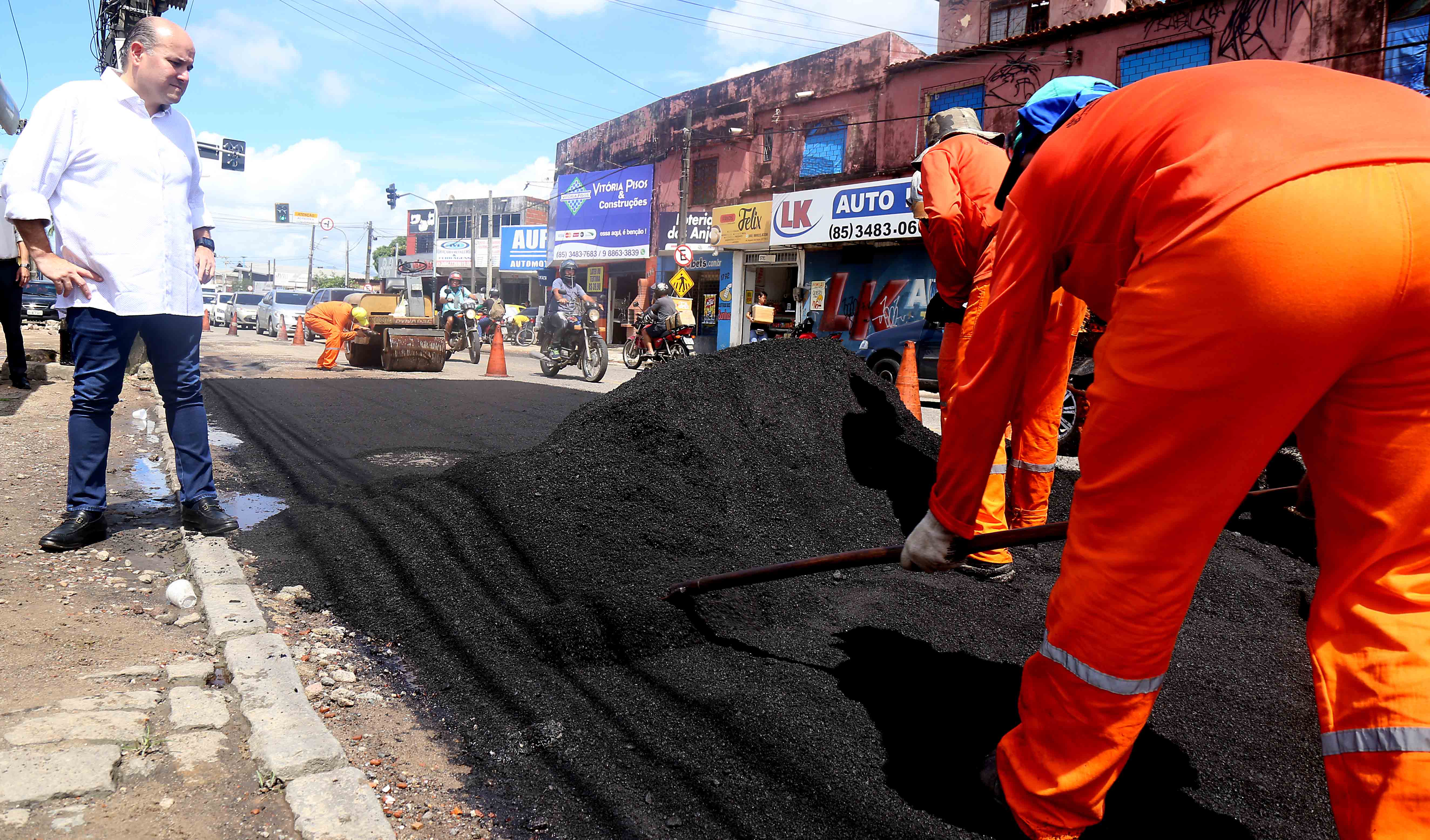 Prefeito observa homens trabalhando em obra de recuperação de asfalto