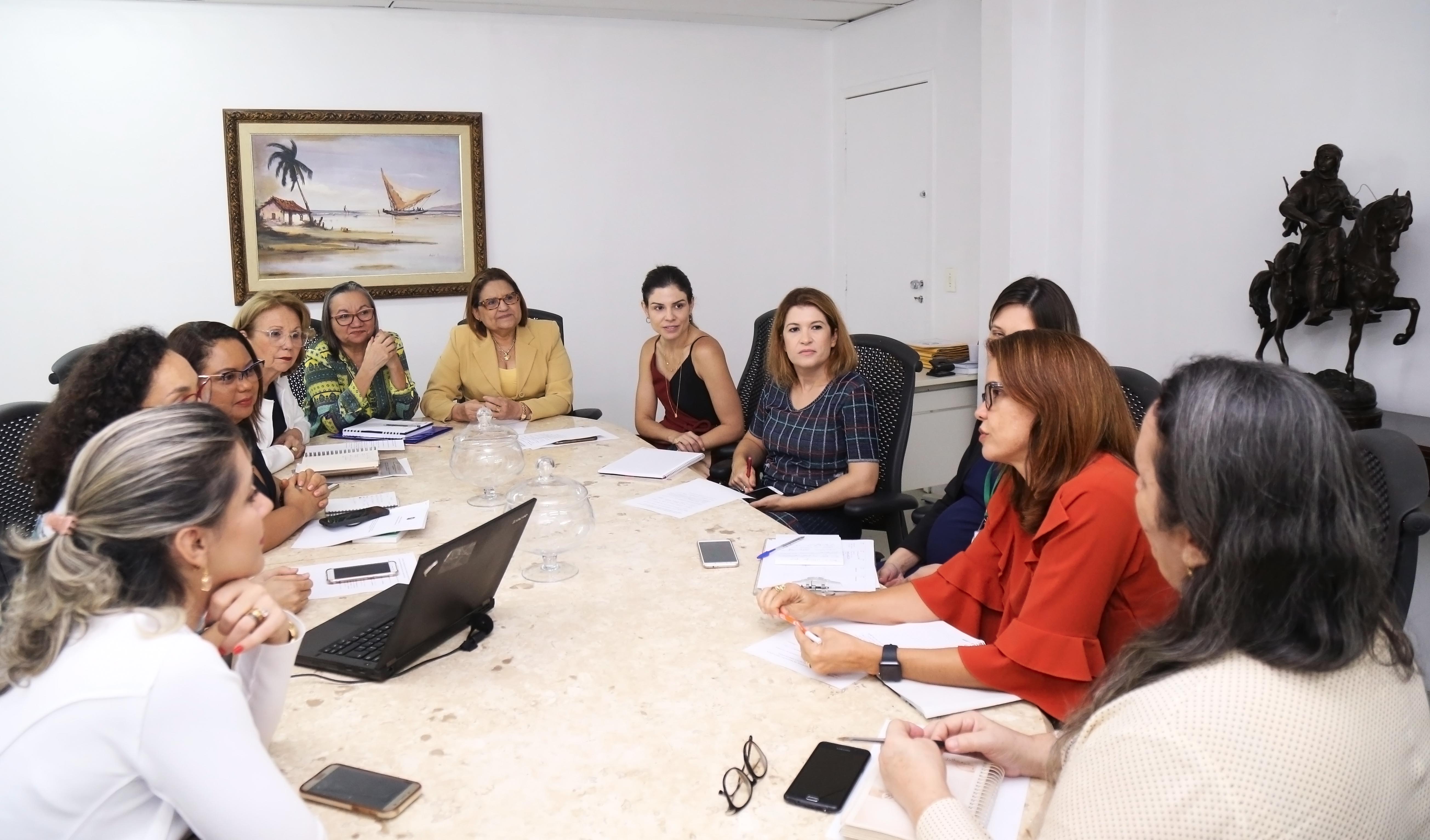 Primeira-dama em uma grande mesa conversando com outras mulheres