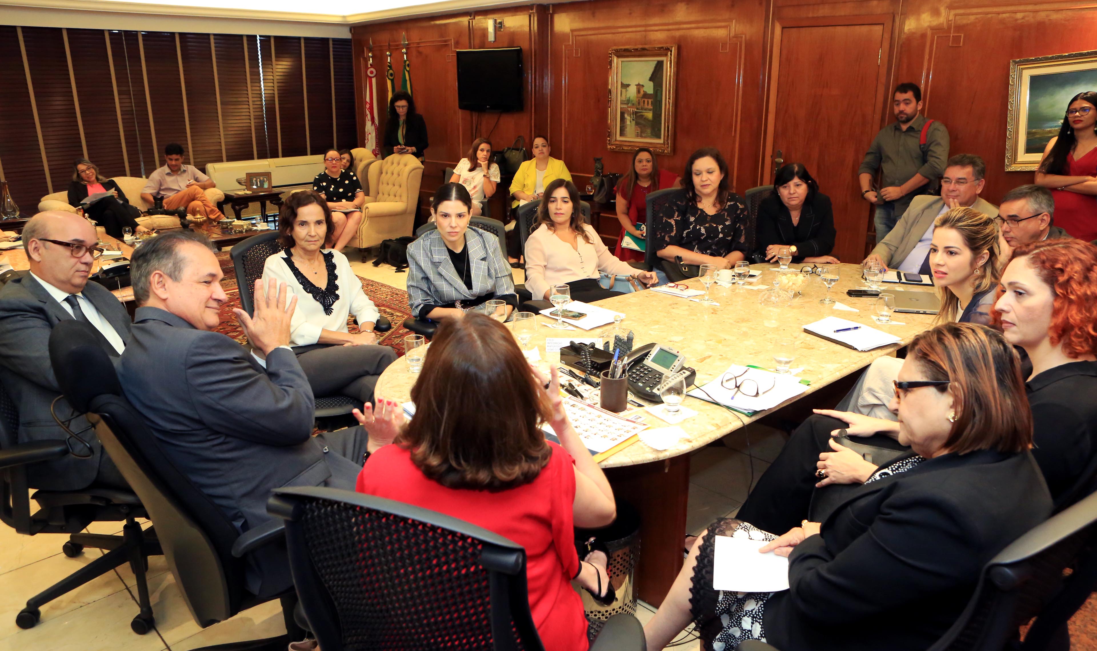 Primeira-dama em grande mesa de reunião com várias pessoas