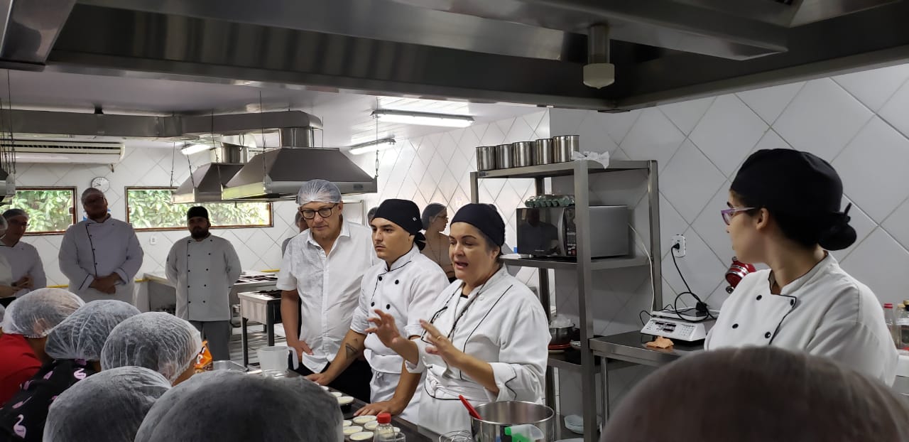 Mulher falando para pessoas reunidas em uma cozinha