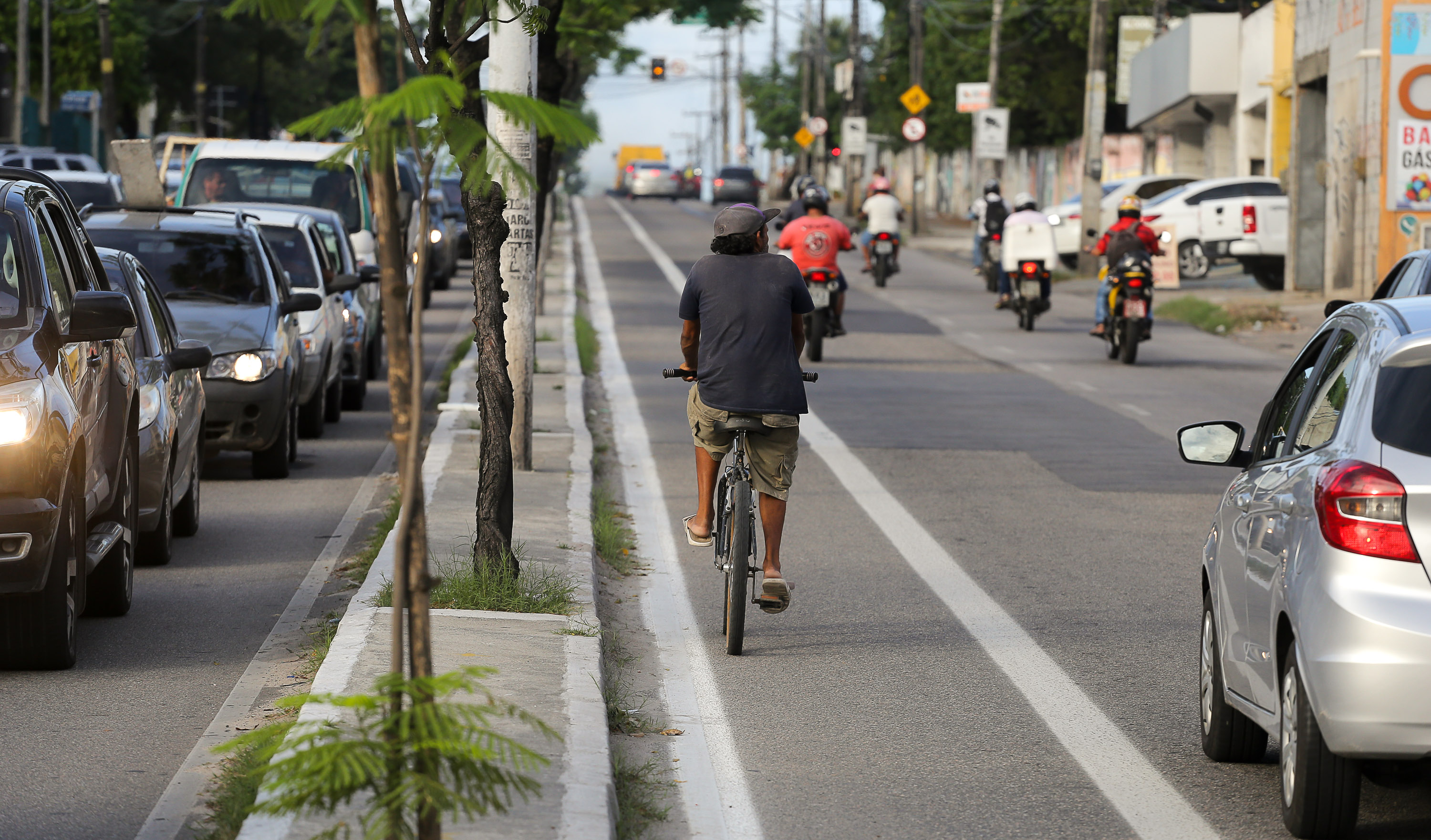Ciclista pedalando em ciclofaixa em avenida