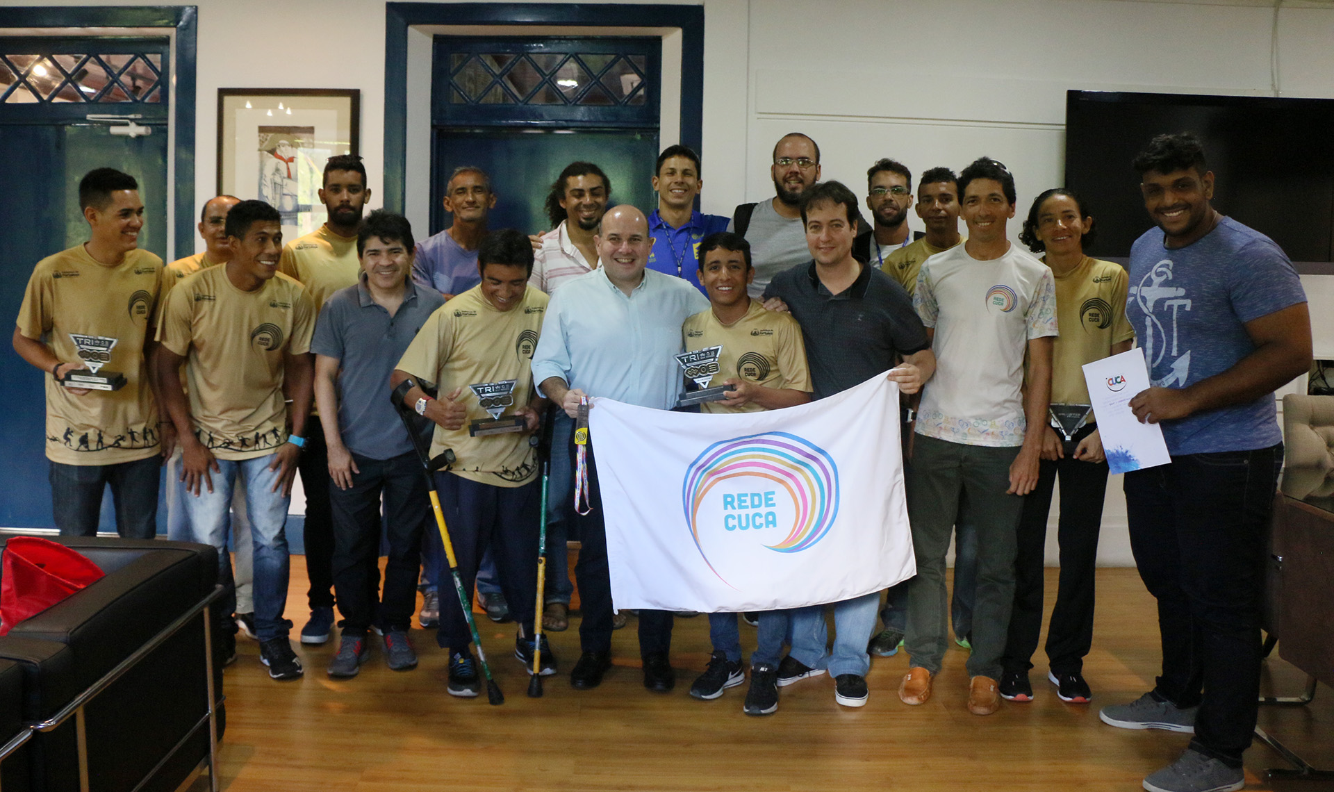 Prefeito e jovens em pé mostrando suas passagens e troféus