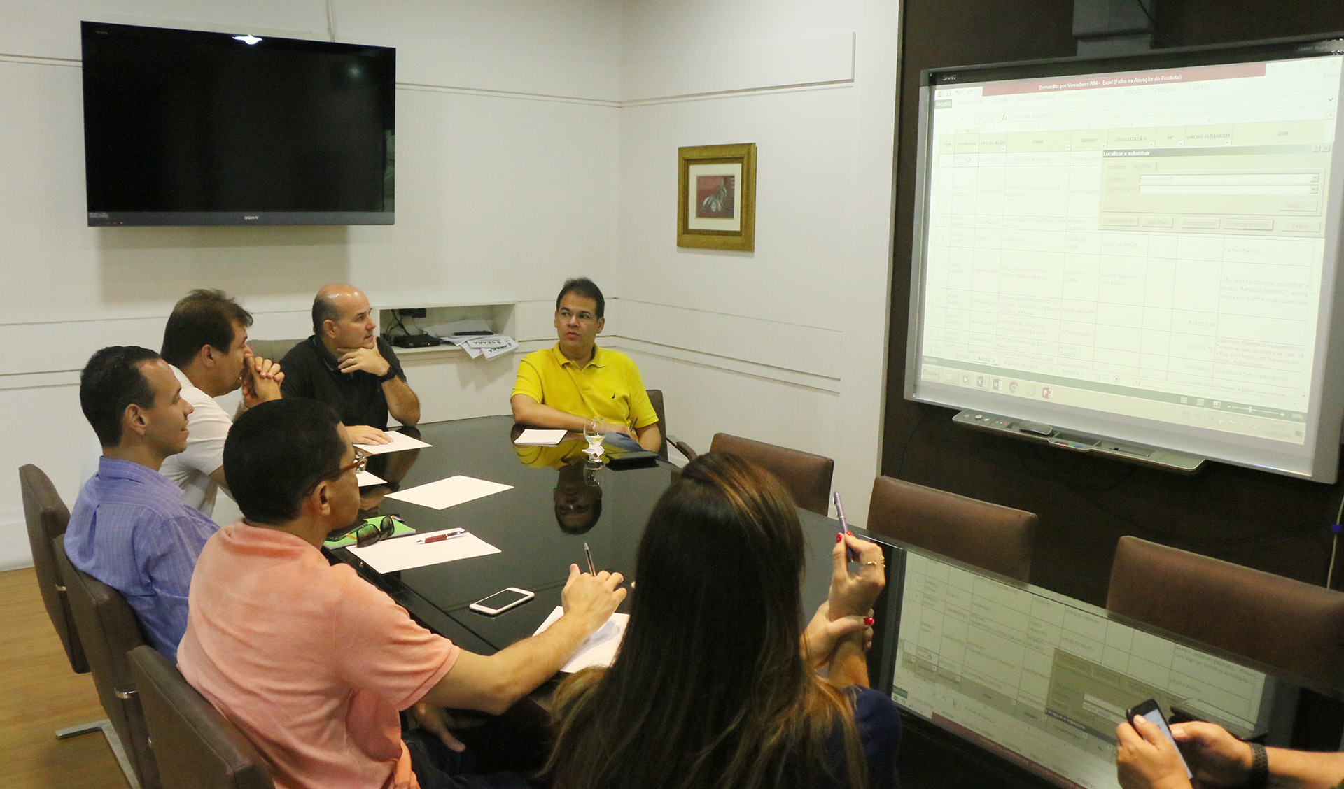 Prefeito sentado em mesa conversando com secretários