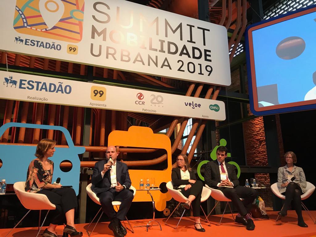 Prefeito fala ao microfone sentado ao lado de quatro pessoas