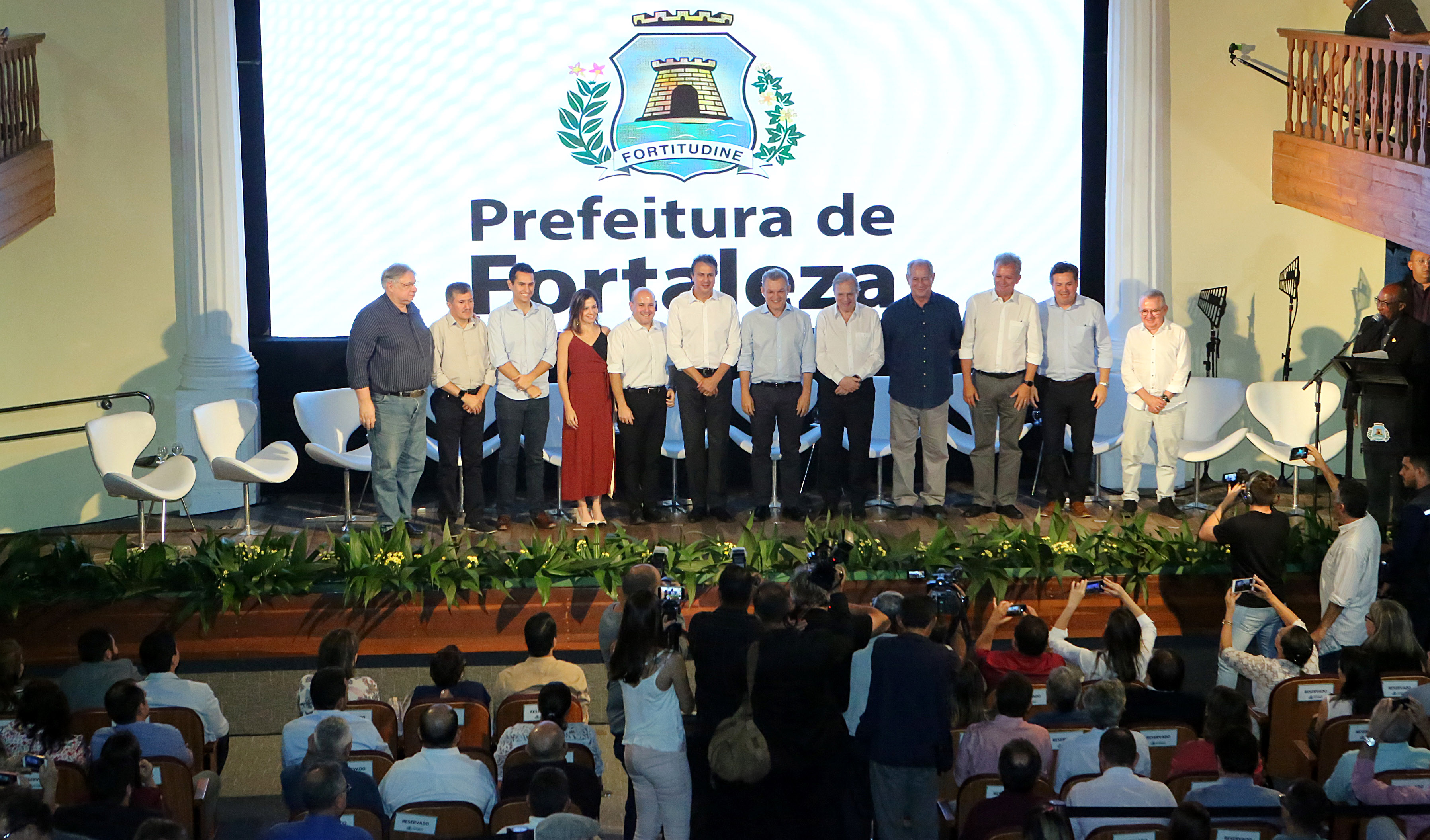 Prefeito e demais convidados sentados em cima de palco