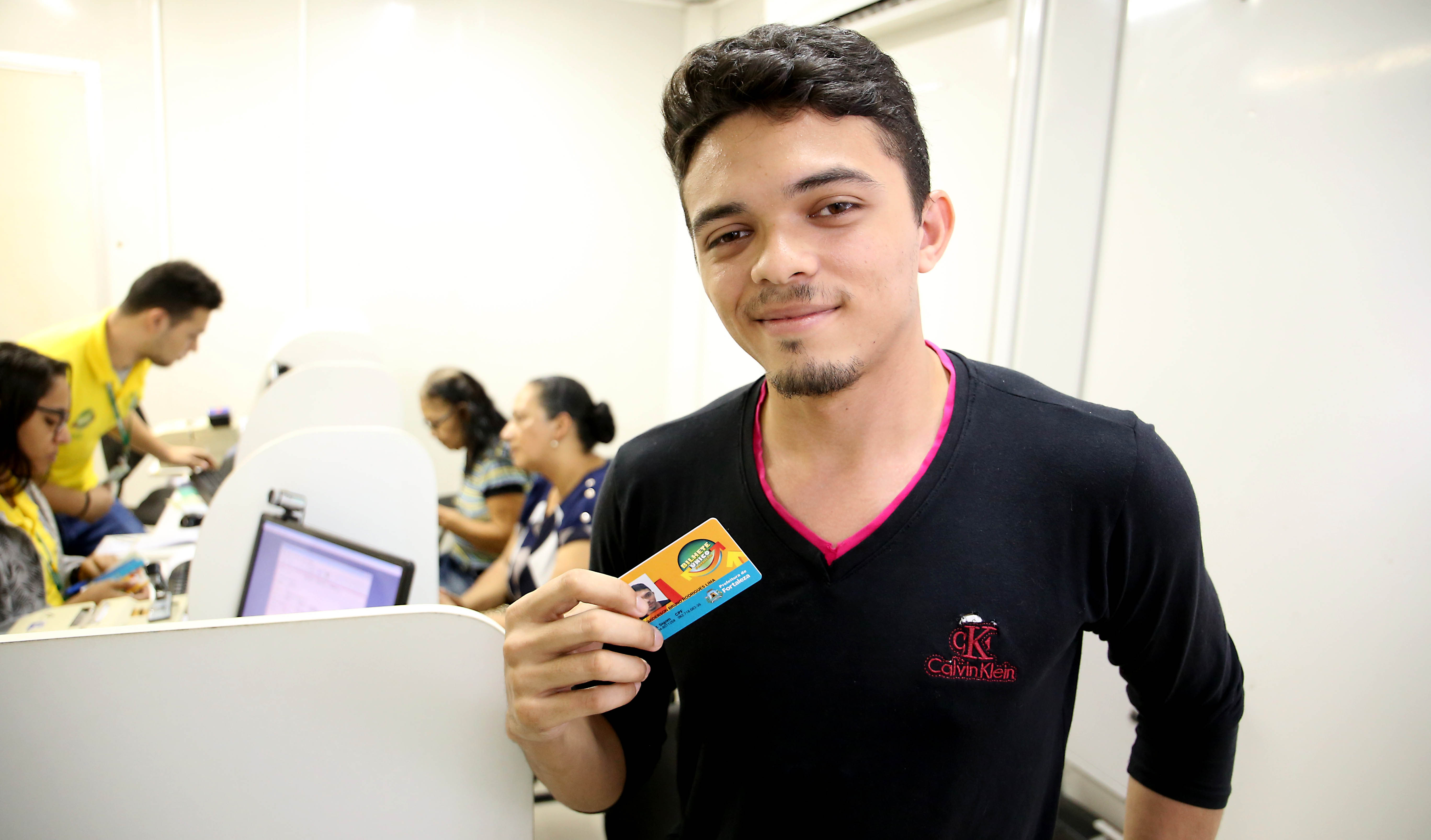 Rapaz sorrindo e segurando cartão do Bilhete Único