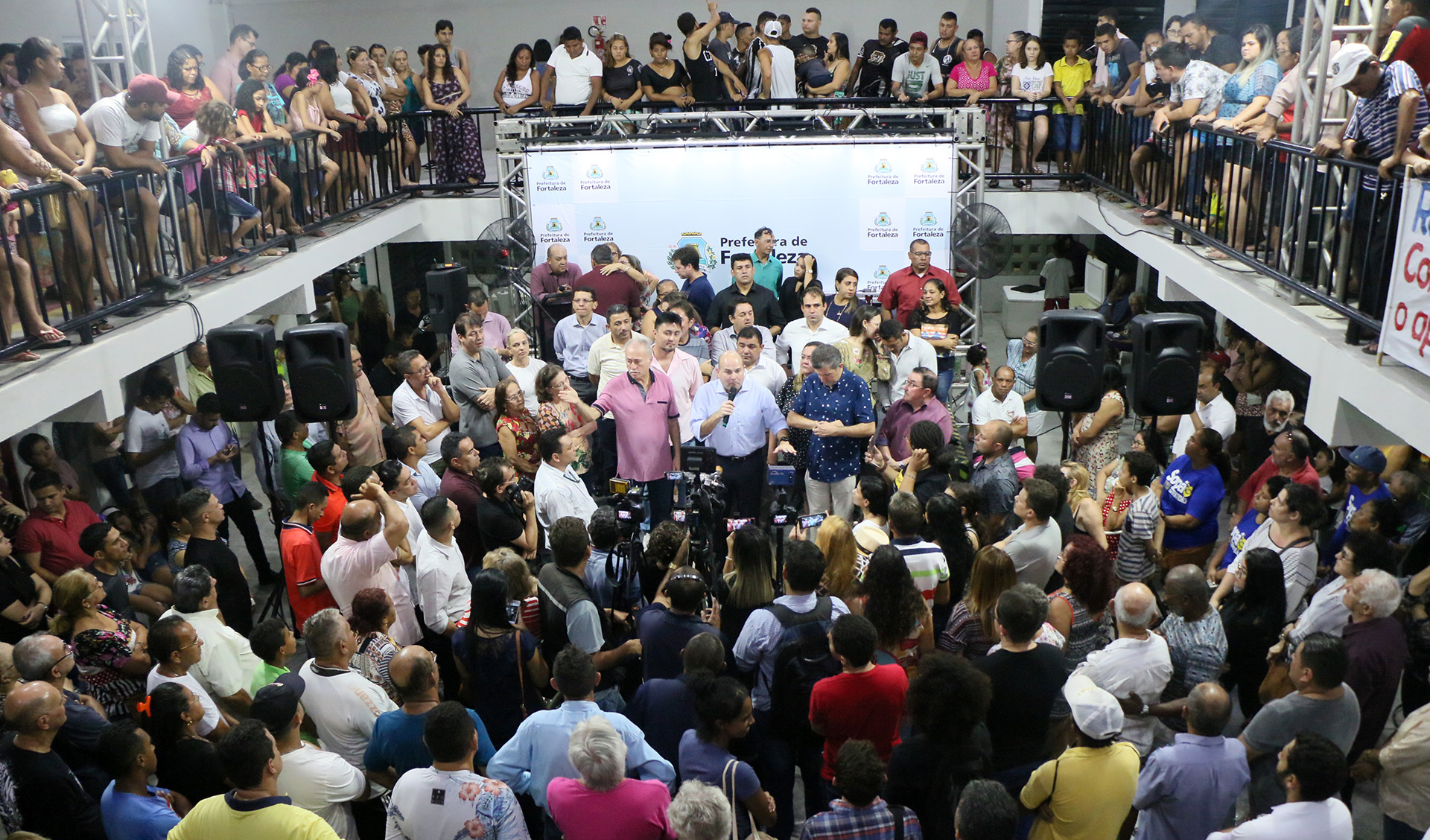Muitas pessoas ao redor do prefeito falando em palco