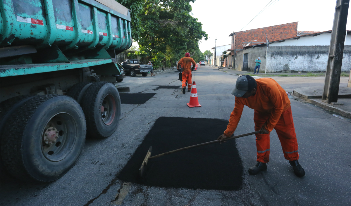 Homens tapando buraco em asfalto
