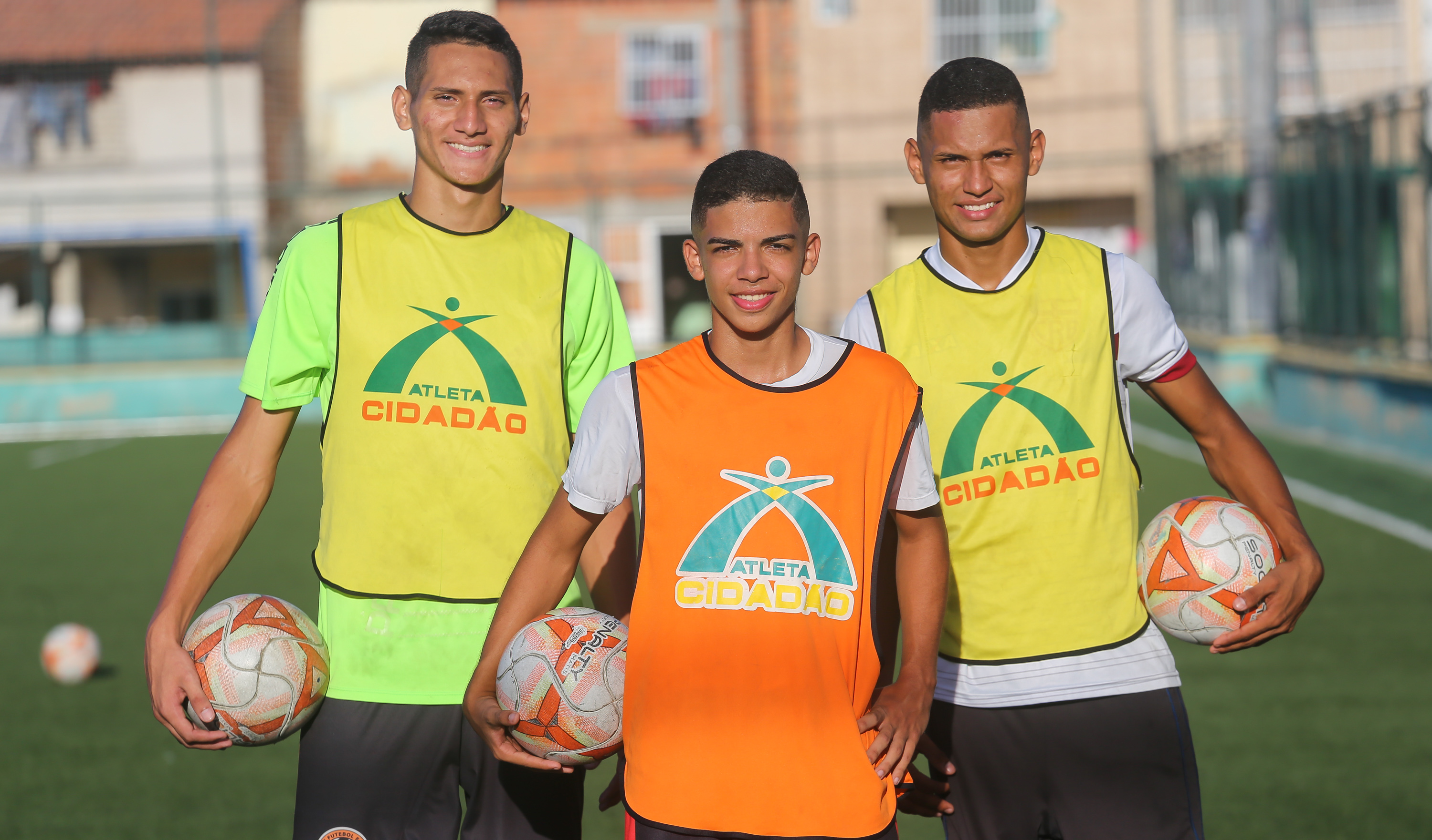 Três jovens jogadores posando para foto segurando bolas