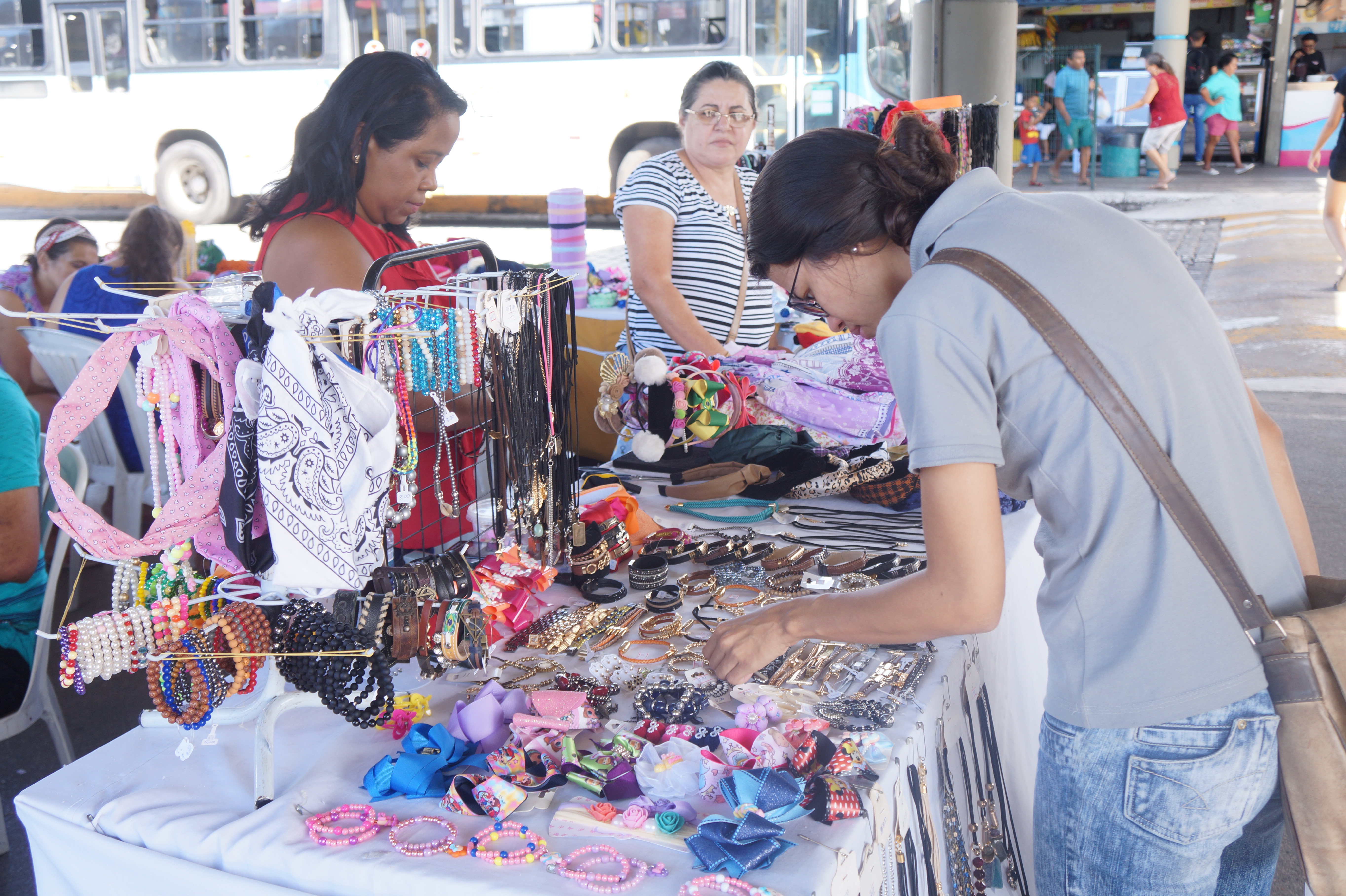 Duas mulheres vendo produtos em mesa de feirinha no terminal