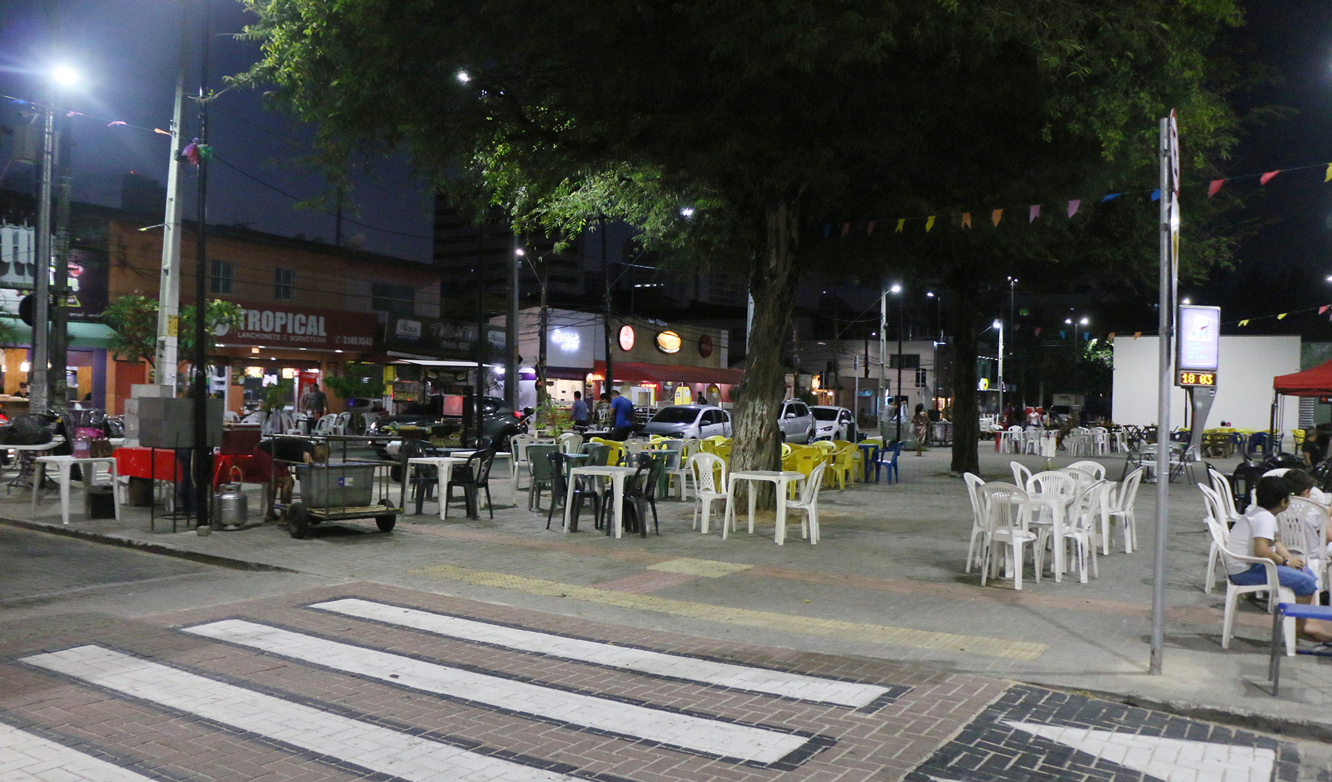 Praça com mesas e cadeiras, árvores