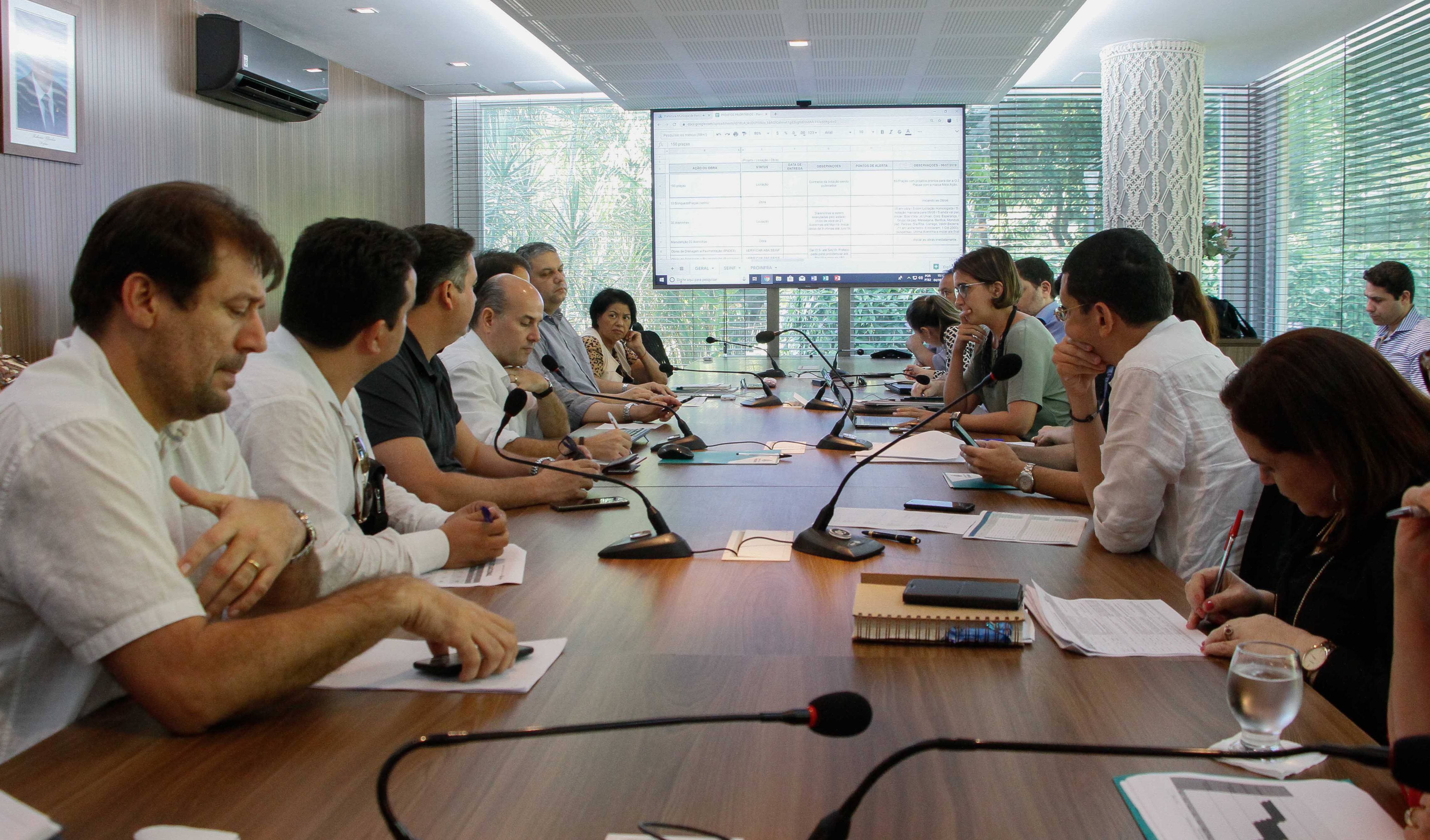 Prefeito e secretários sentados ao redor de mesa conversando