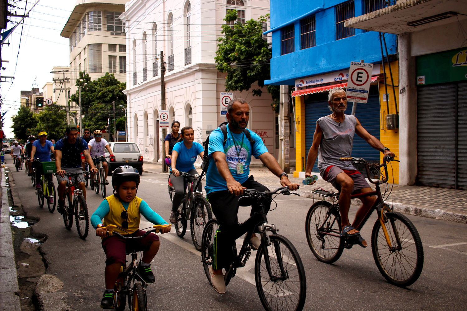 Dois ciclistas adultos e um ciclista criança guiando bicicletas na rua