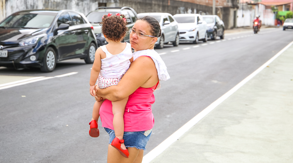 Mulher com criança no colo atravessando rua
