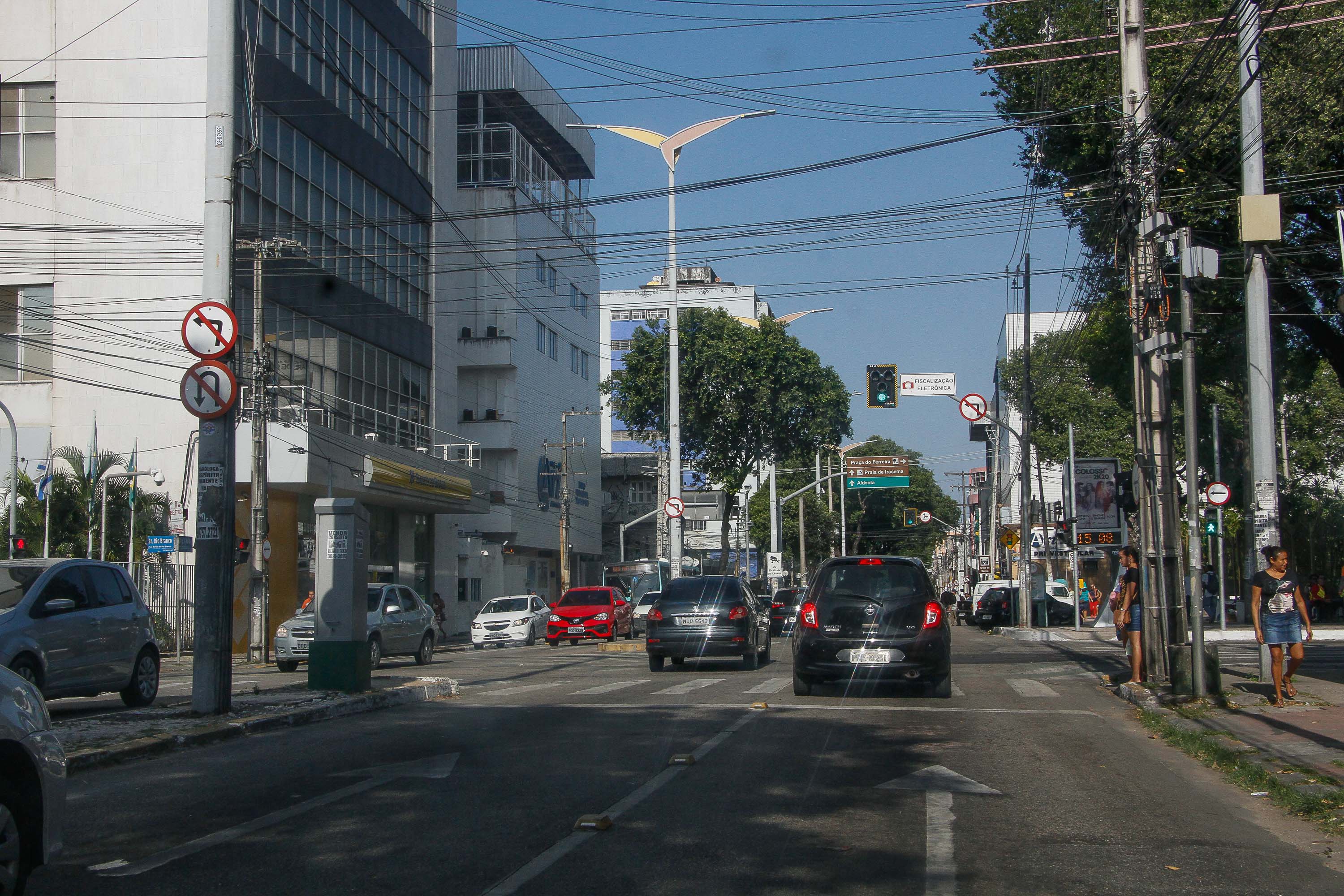 Avenida com canteiro central, carros circulando e semáforo verde