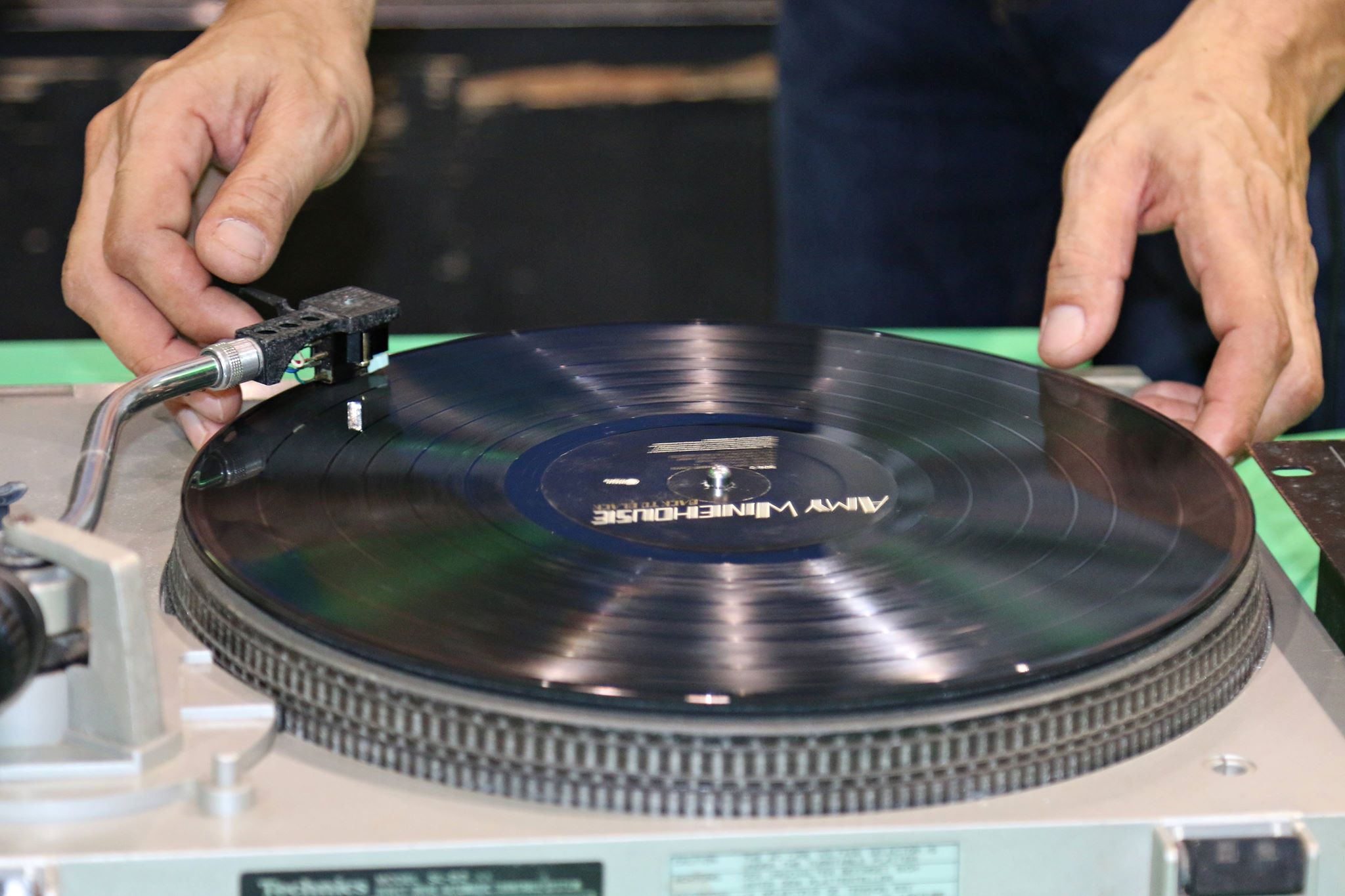 Duas mãos próximas a um disco de vinil que toca em uma pickup de DJ