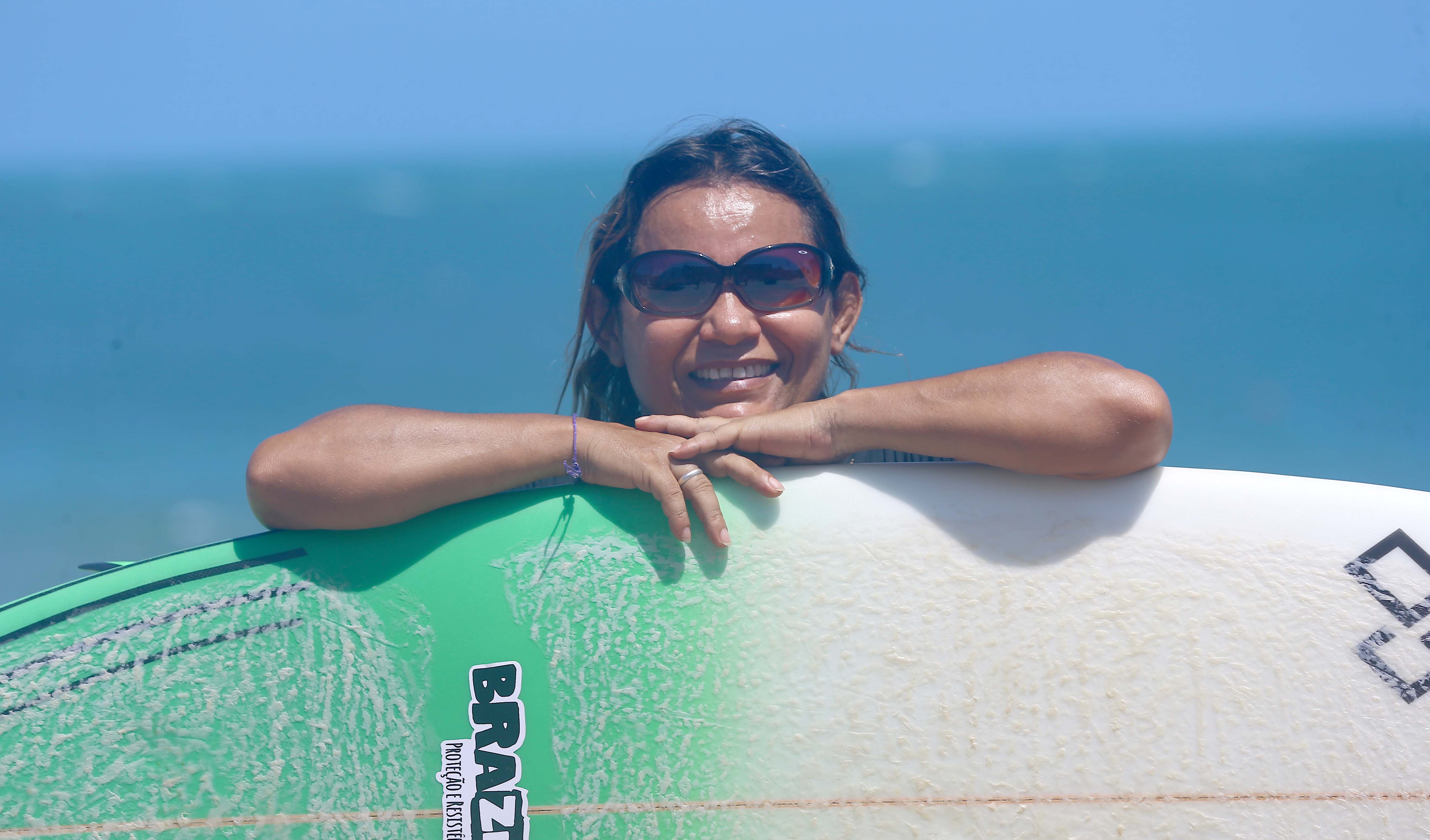 tita tavares posa para a foto segurando uma prancha de surfe