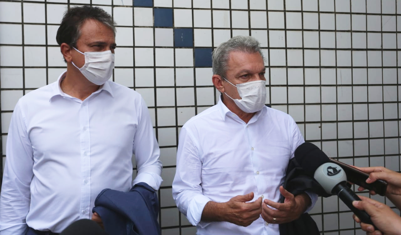 Camilo Santana e José Sarto lado a lado falando em frente a mãos segurando microfones