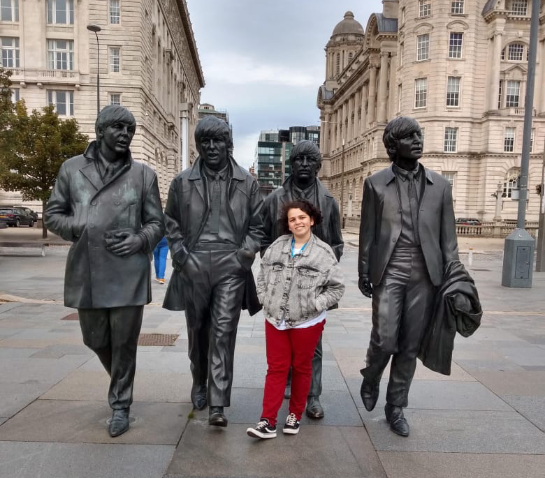 moça jovem posando para foto em frente às estátuas dos beatles