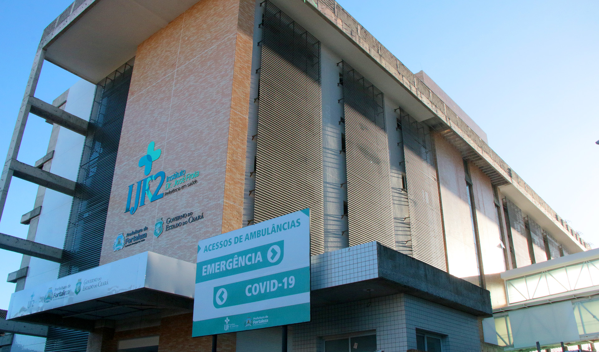 fachada do IJF com placas com nome do hospital, marcas da prefeitura e do governo do estado e o texto Covid-19