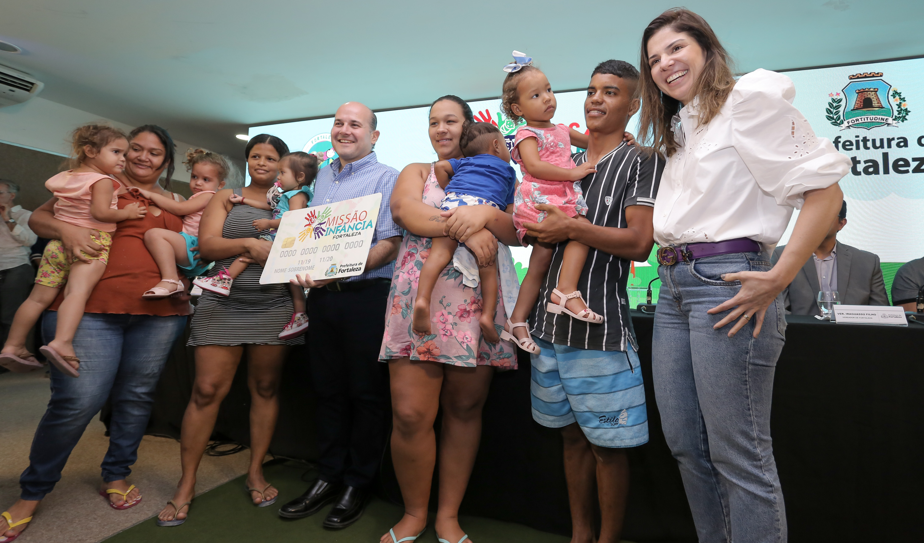 prefeito e primeira dama entregando cartões para família com crianças no colo e posando para foto