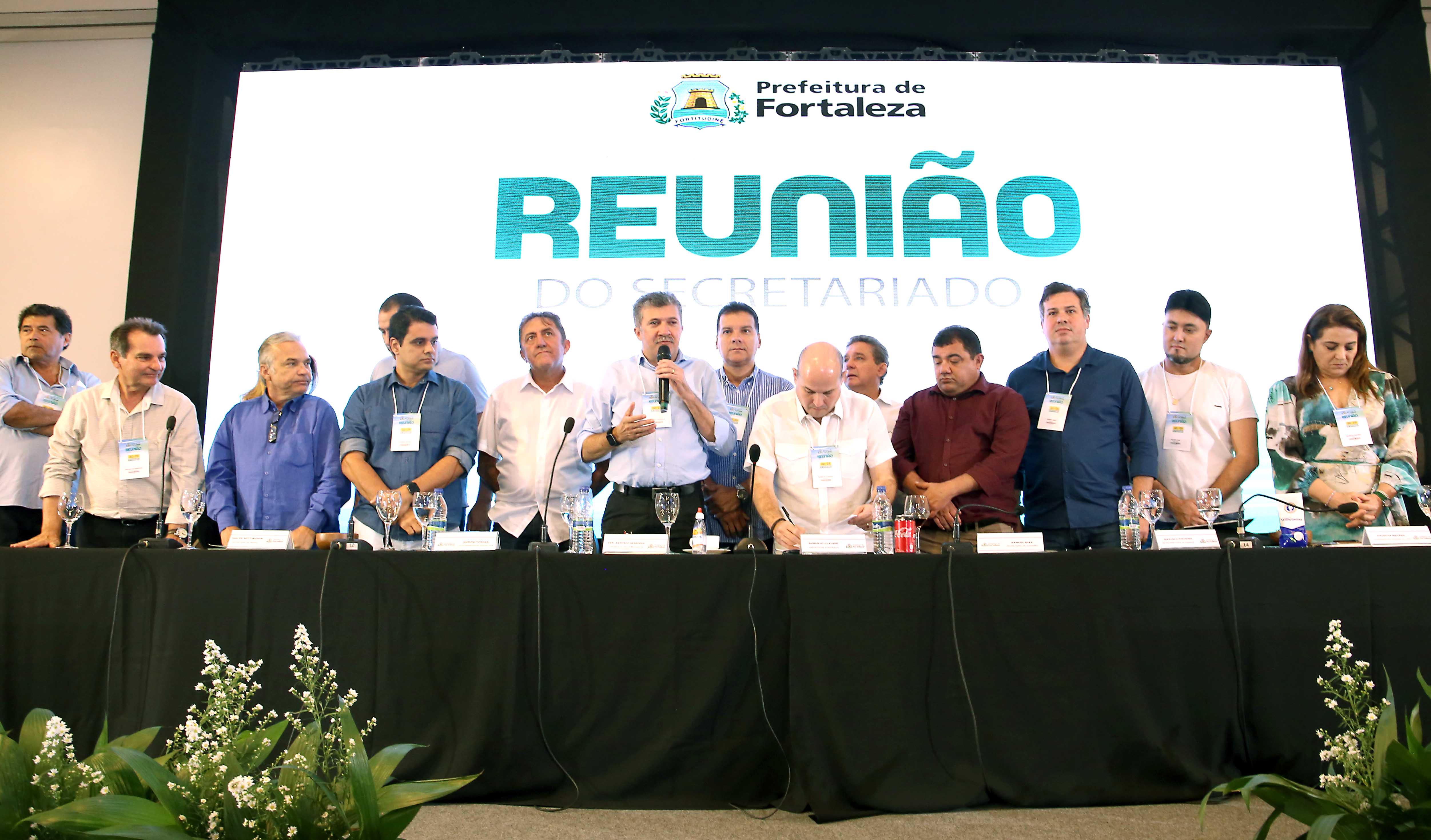 prefeito assina documento cercado por um grupo de homens