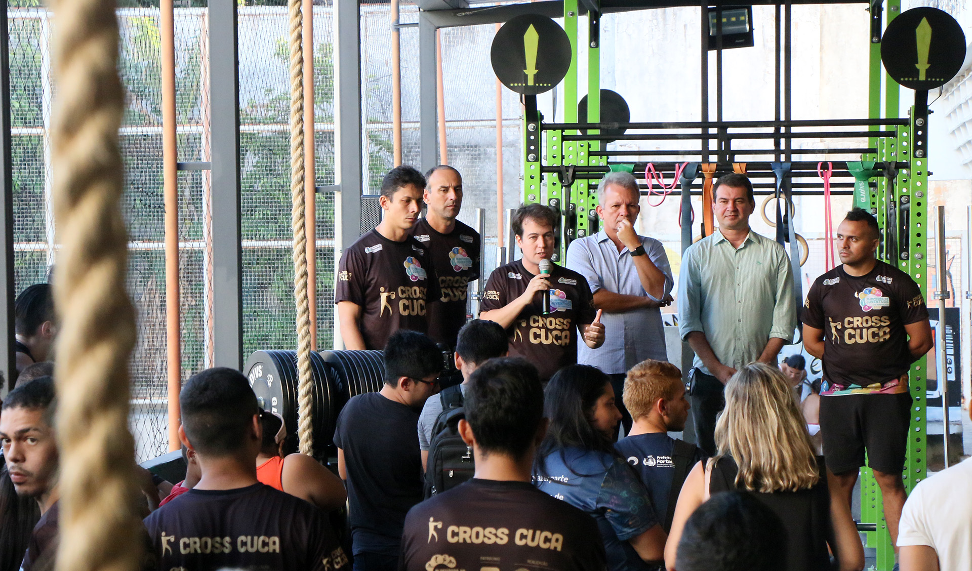 homens em cima de palco em frente a jovens sentados no chão assistindo