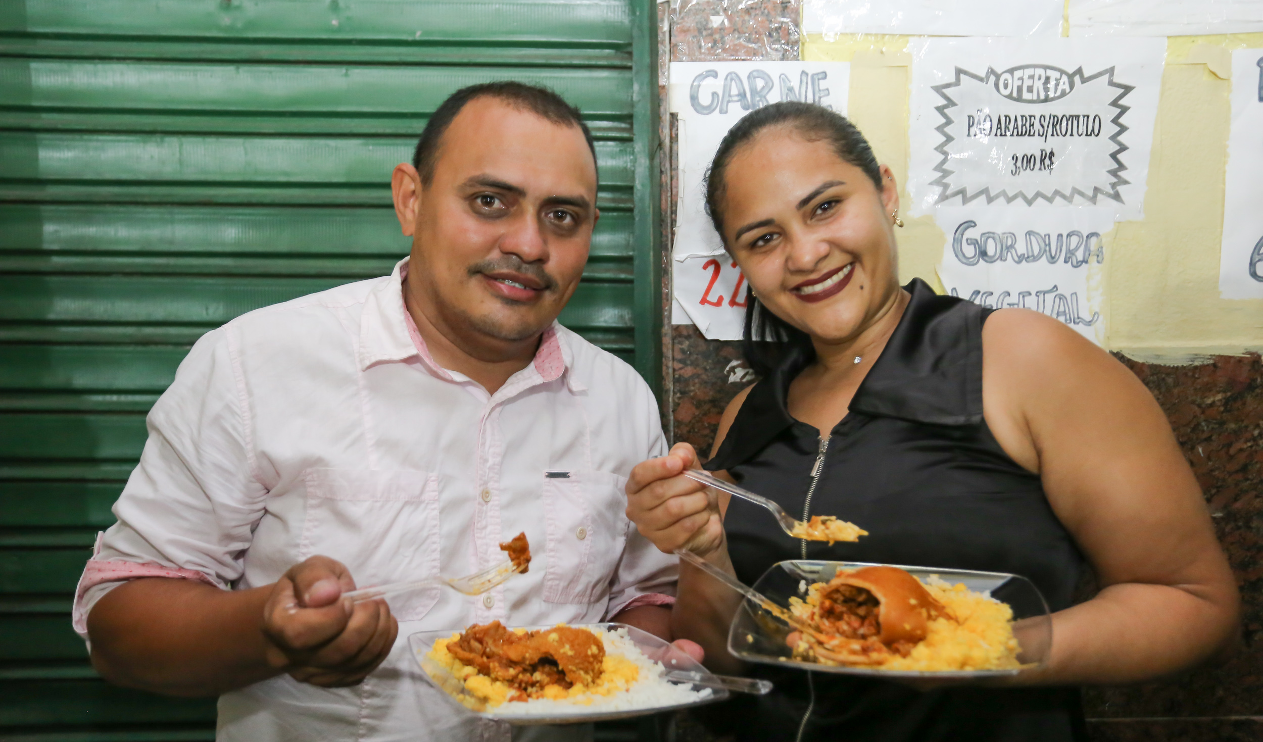 homem e mulher sorrindo segurando prato de buchada