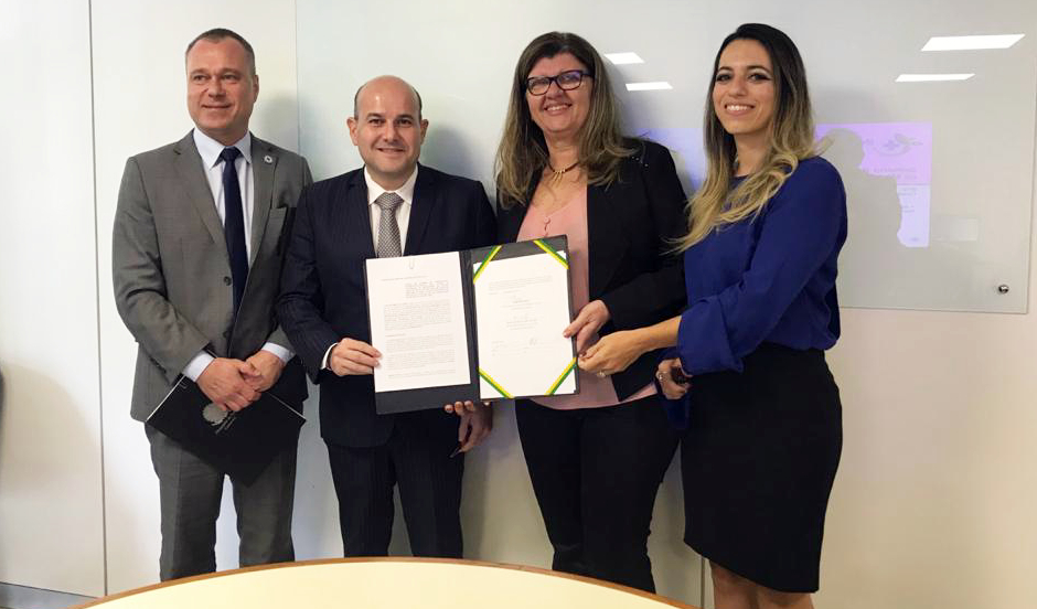 prefeito, senhor e duas mulheres em pé posando para a foto segurando documento