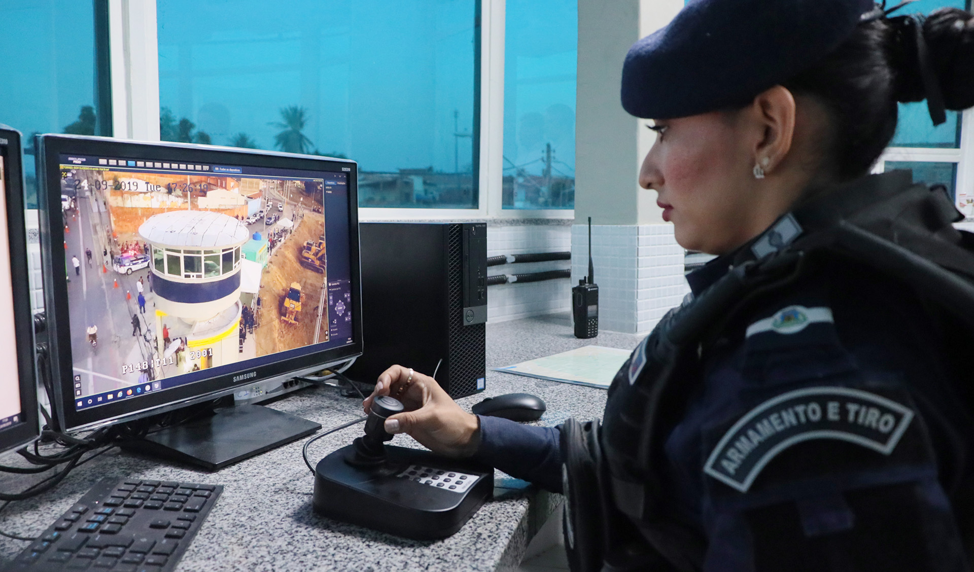 guarda municipal mulher de perfil olhando para monitor com imagens de câmeras de segurança