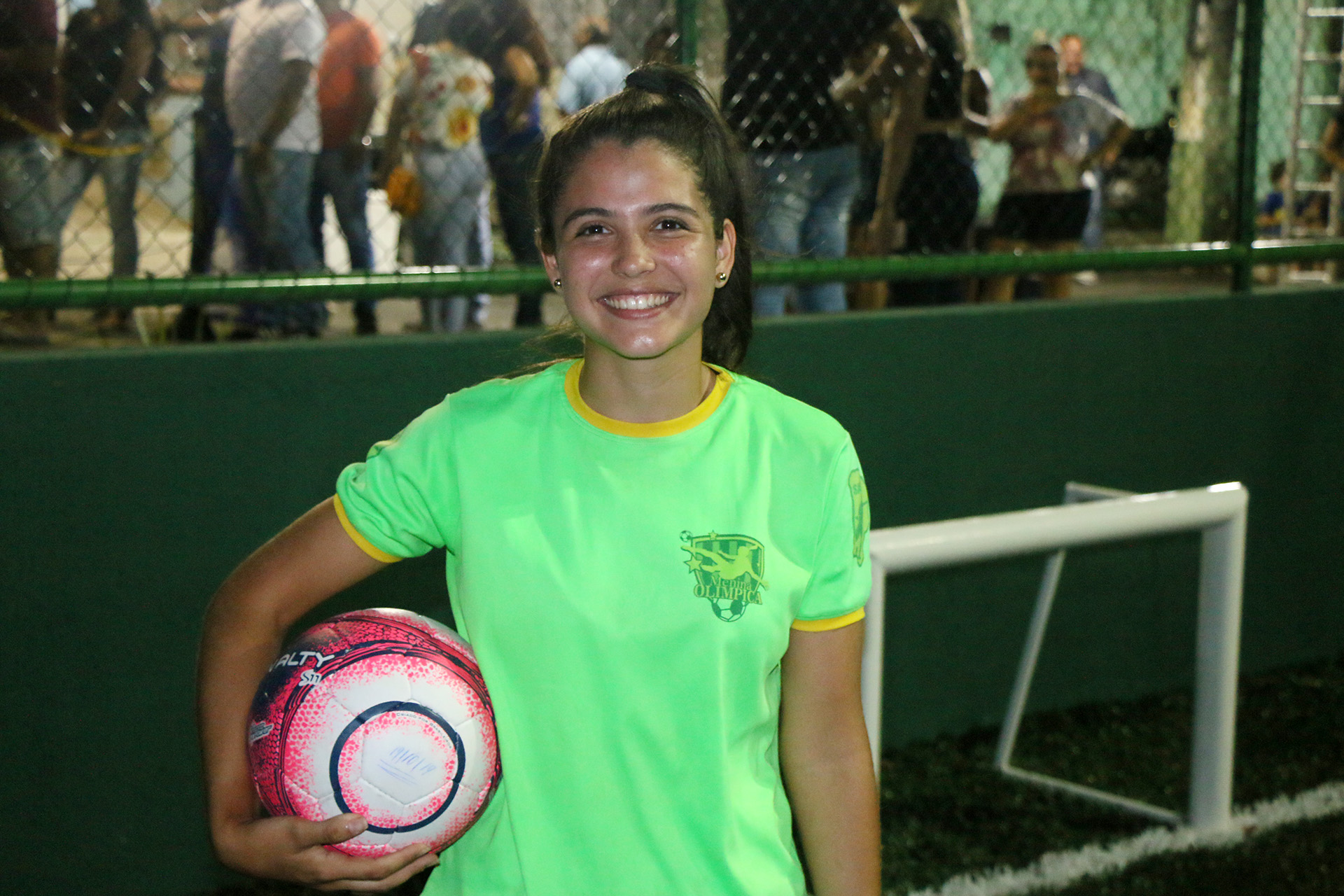 adolescente de camisa verde posa para a foto sorrindo