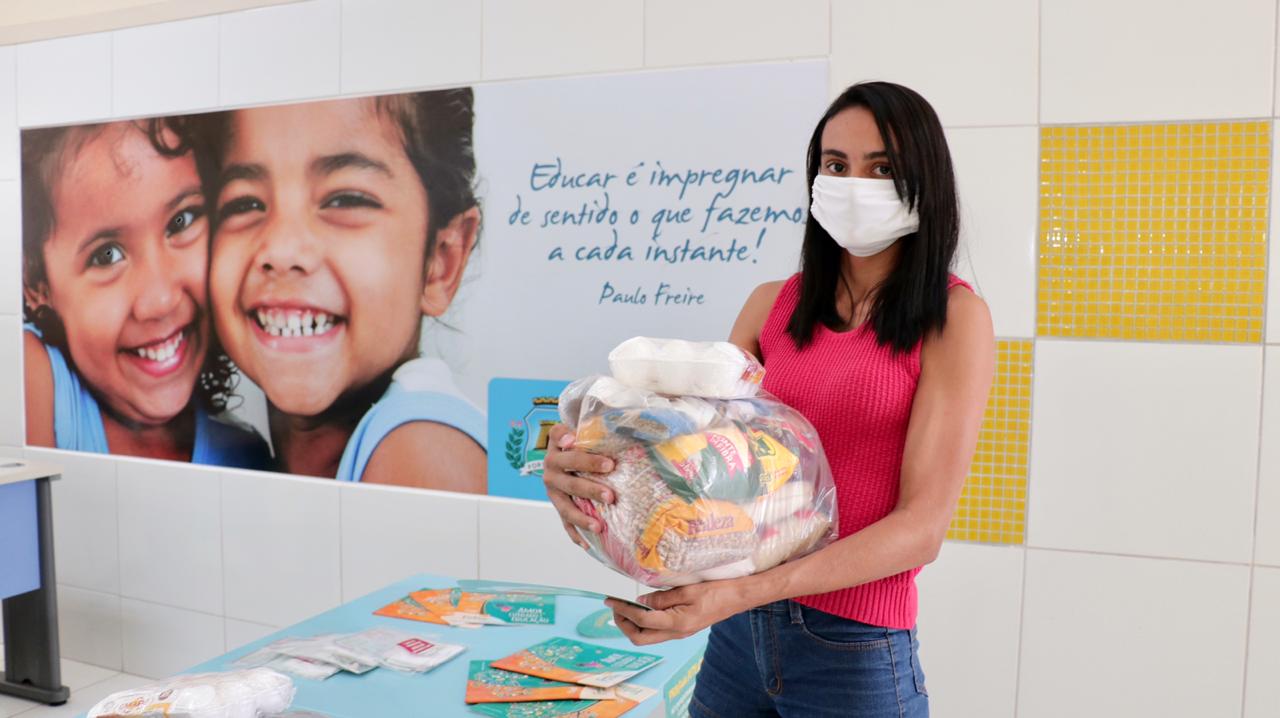 Uma mãe de aluno segurando um kit de alimentação