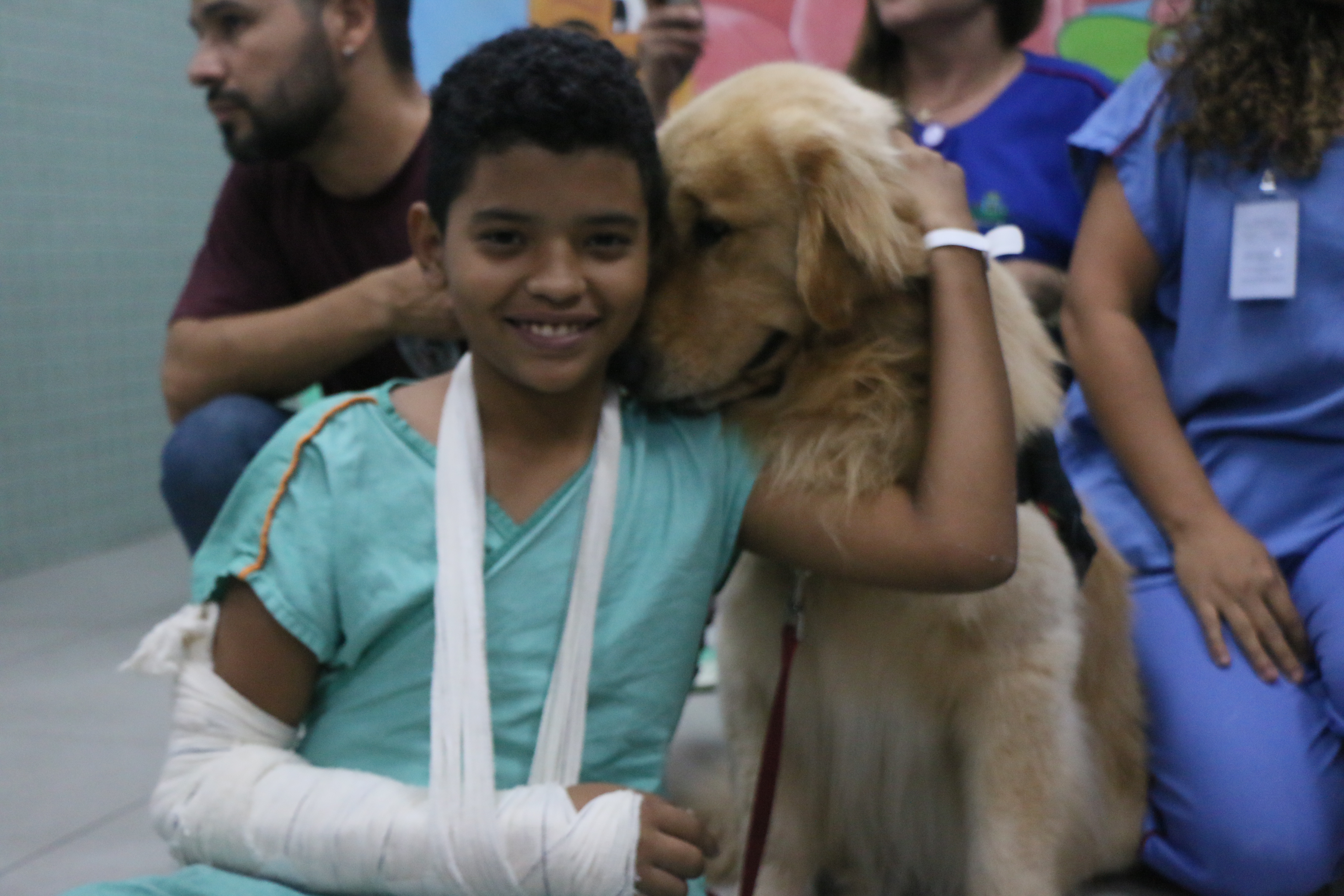 garoto com braço engessado abraçado com cachorro