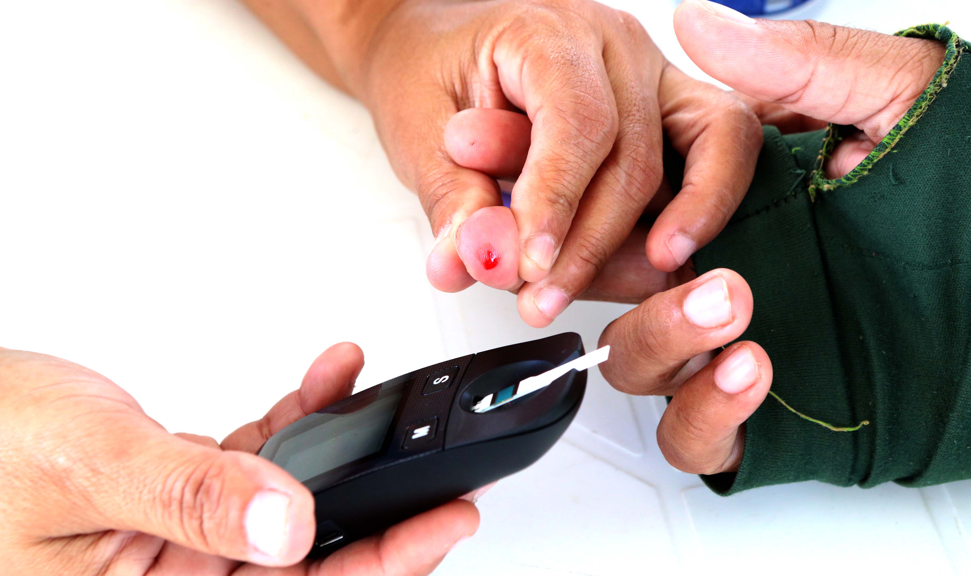teste de diabetes mostrando um enfermeiro aplicando uma agulha na mão de uma pessoa