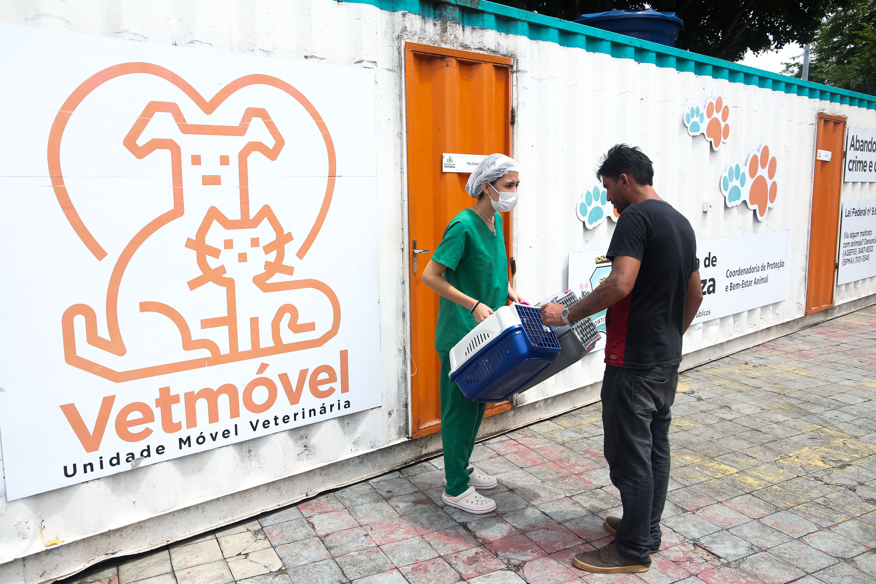 Veterinária recebe caixa de transporte de pet na frente de container do VetMóvel.