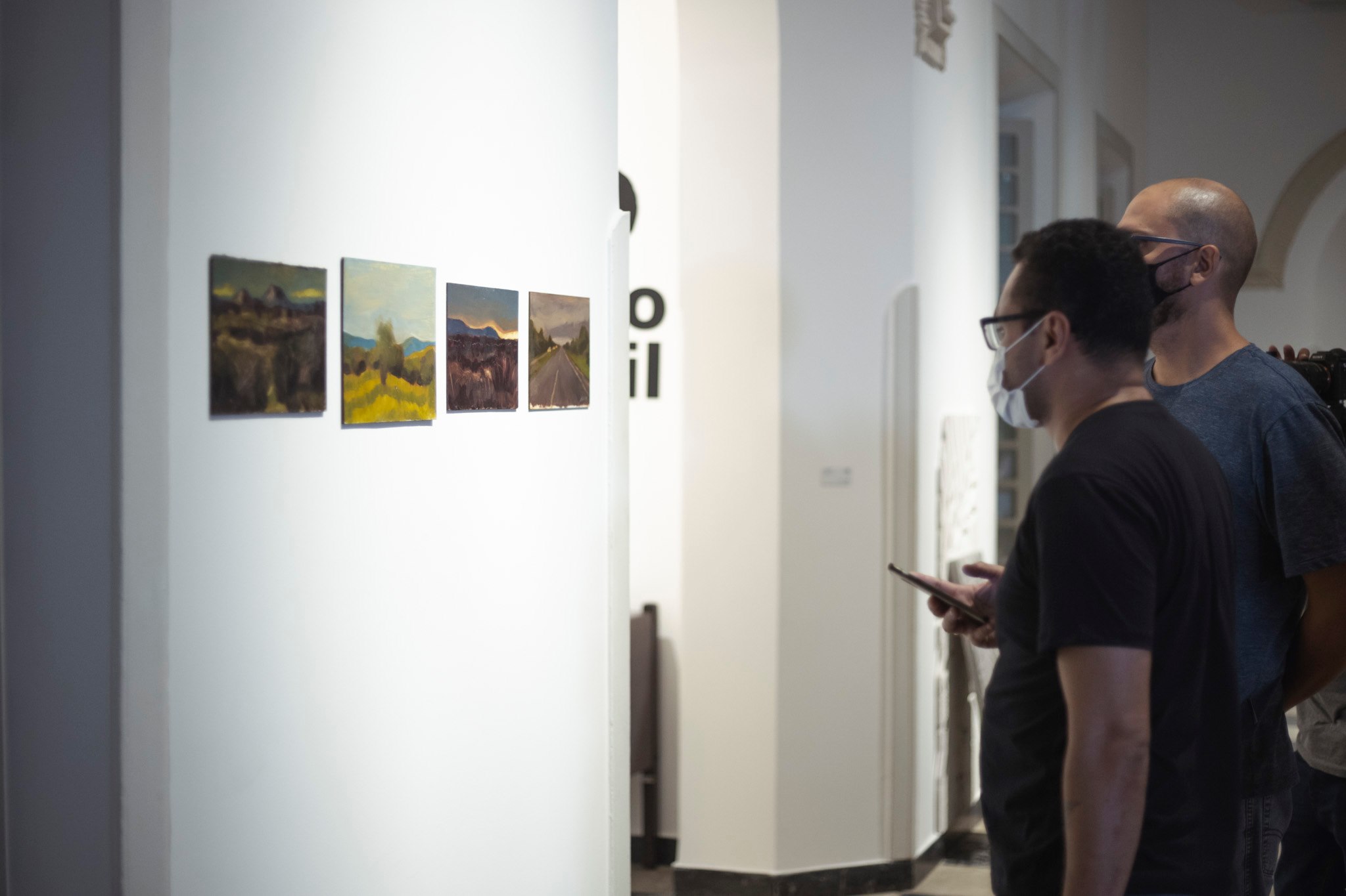 duas pessoas de costas olham quadros na exposição do 71º Salão de Abril