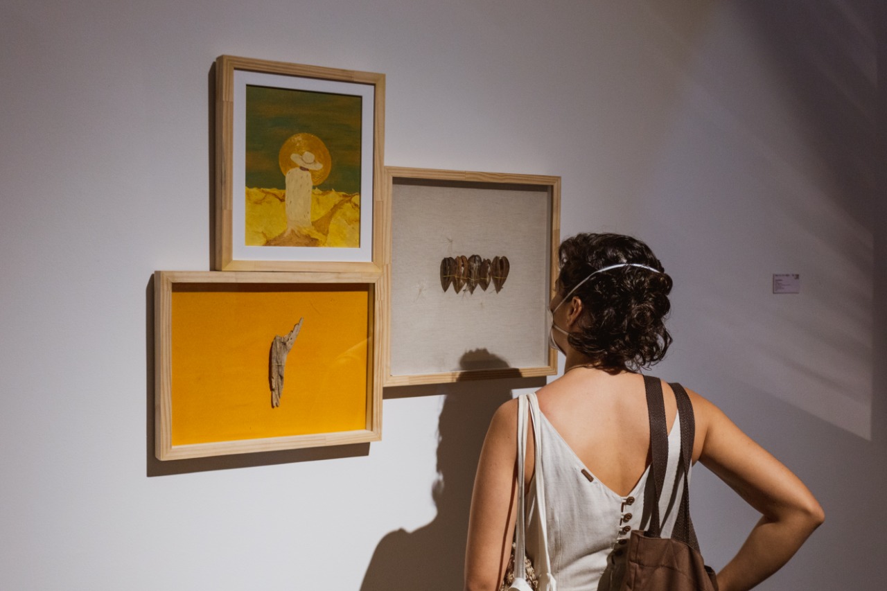 Mulher de costas observa quadro exposto na 72ª edição do Salão de Abril no Centro Cultural Casa do Barão de Camocim