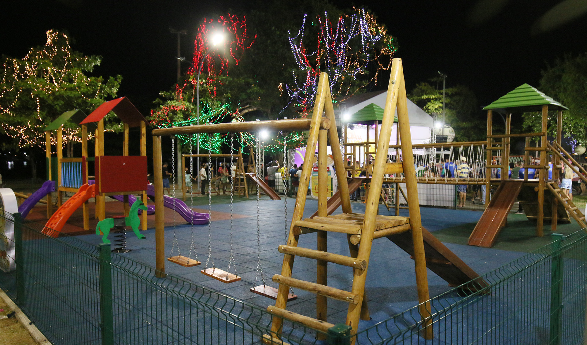 parque infantil a noite com árvores iluminadas ao redor