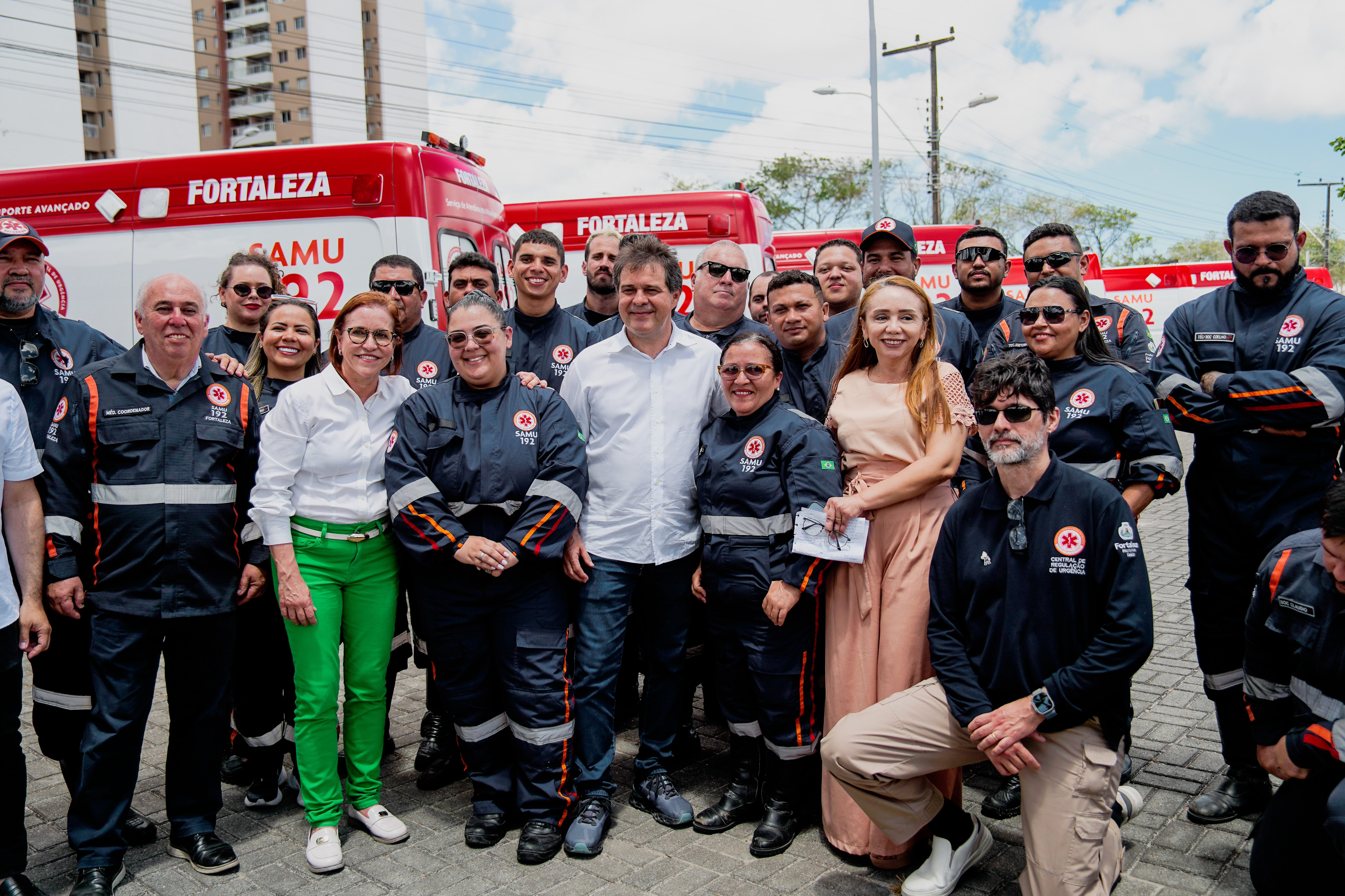 grupo de pessoas posa para a foto na frente das ambulâncias