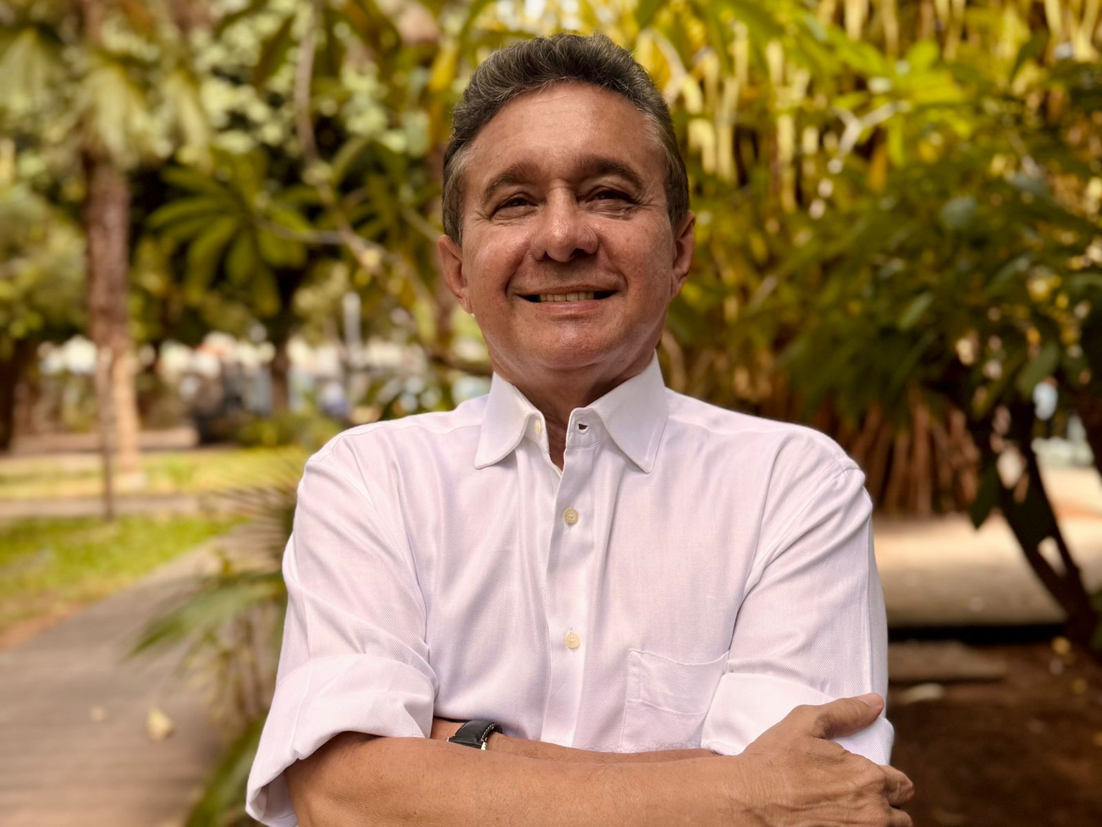 doutor portinho posa para a foto com camisa rosa clara; ele está de braços cruzados