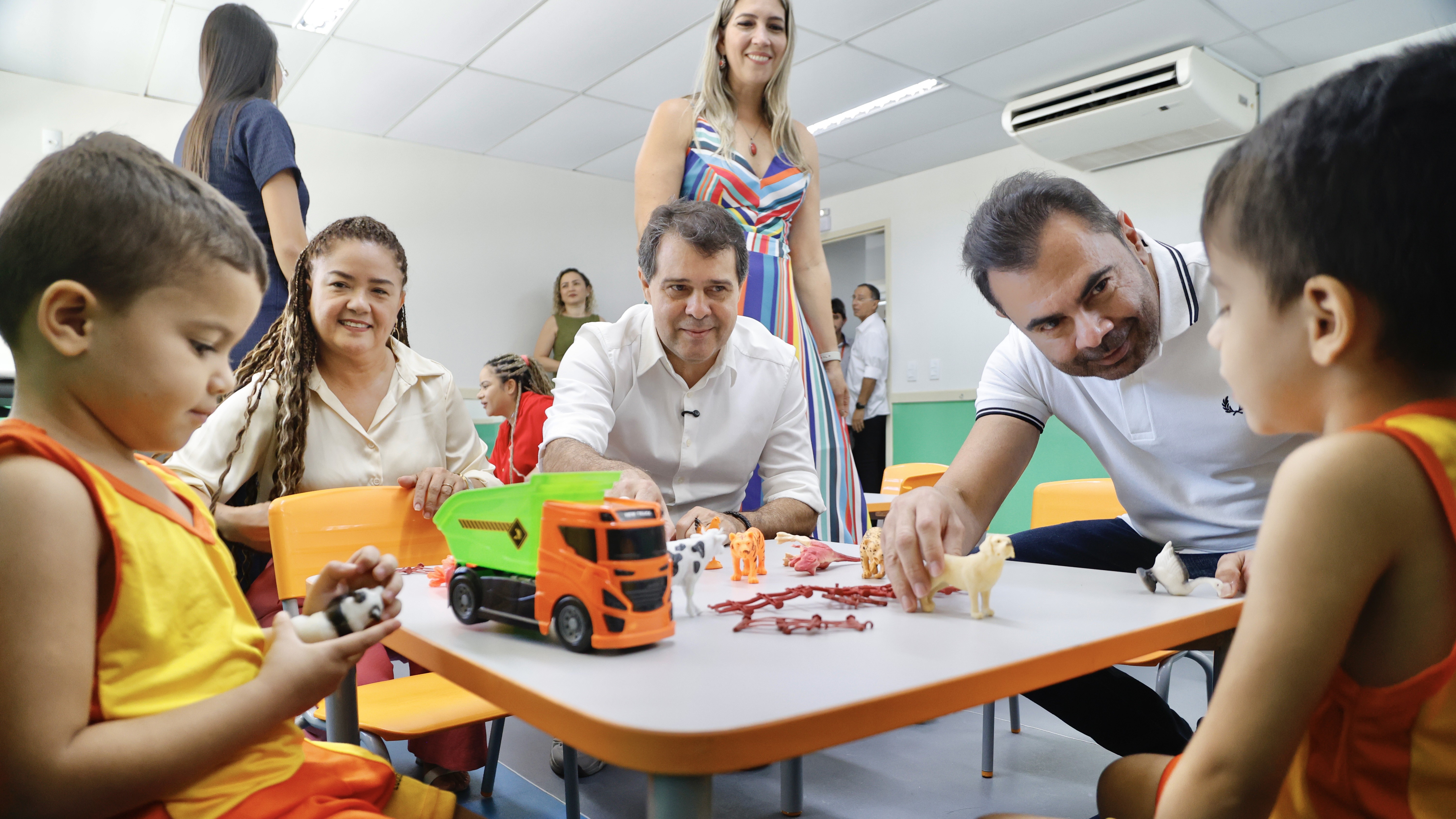 prefeito evandro e secretário idilvan observam alunos brincando em uma mesinha