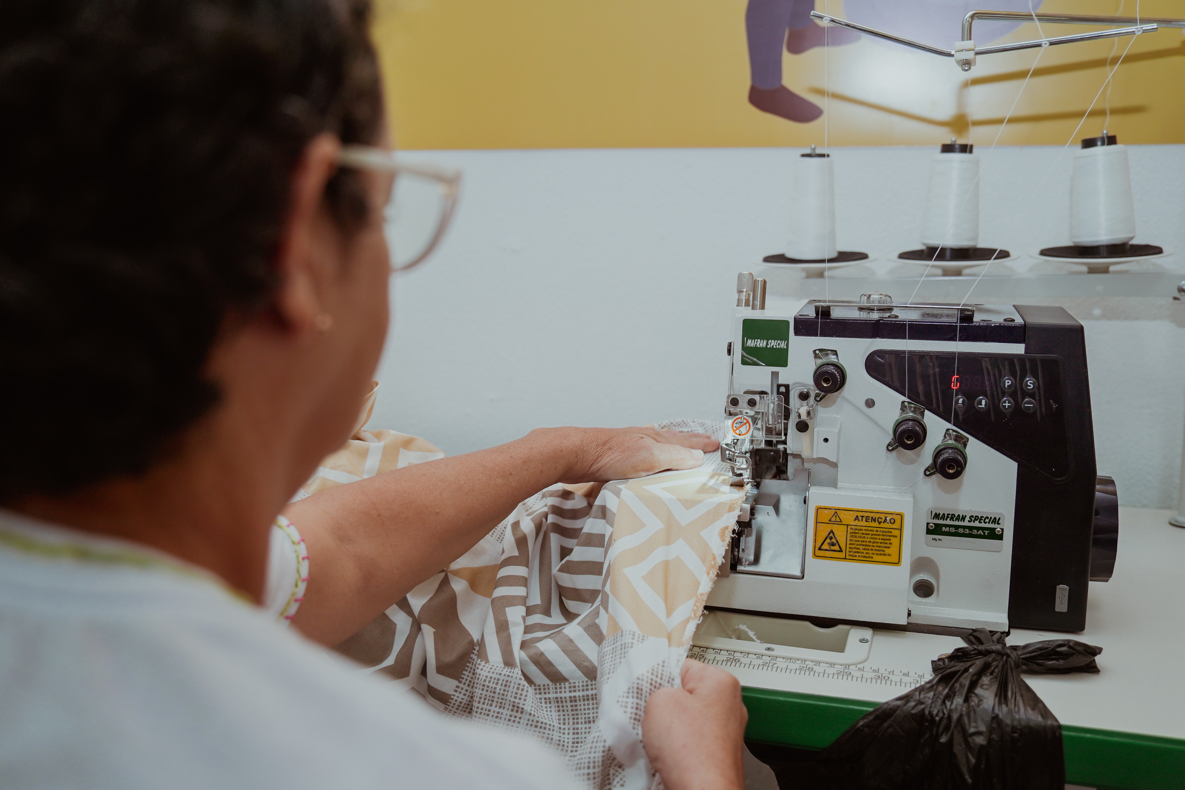 mulher de costas costurando em uma máquina