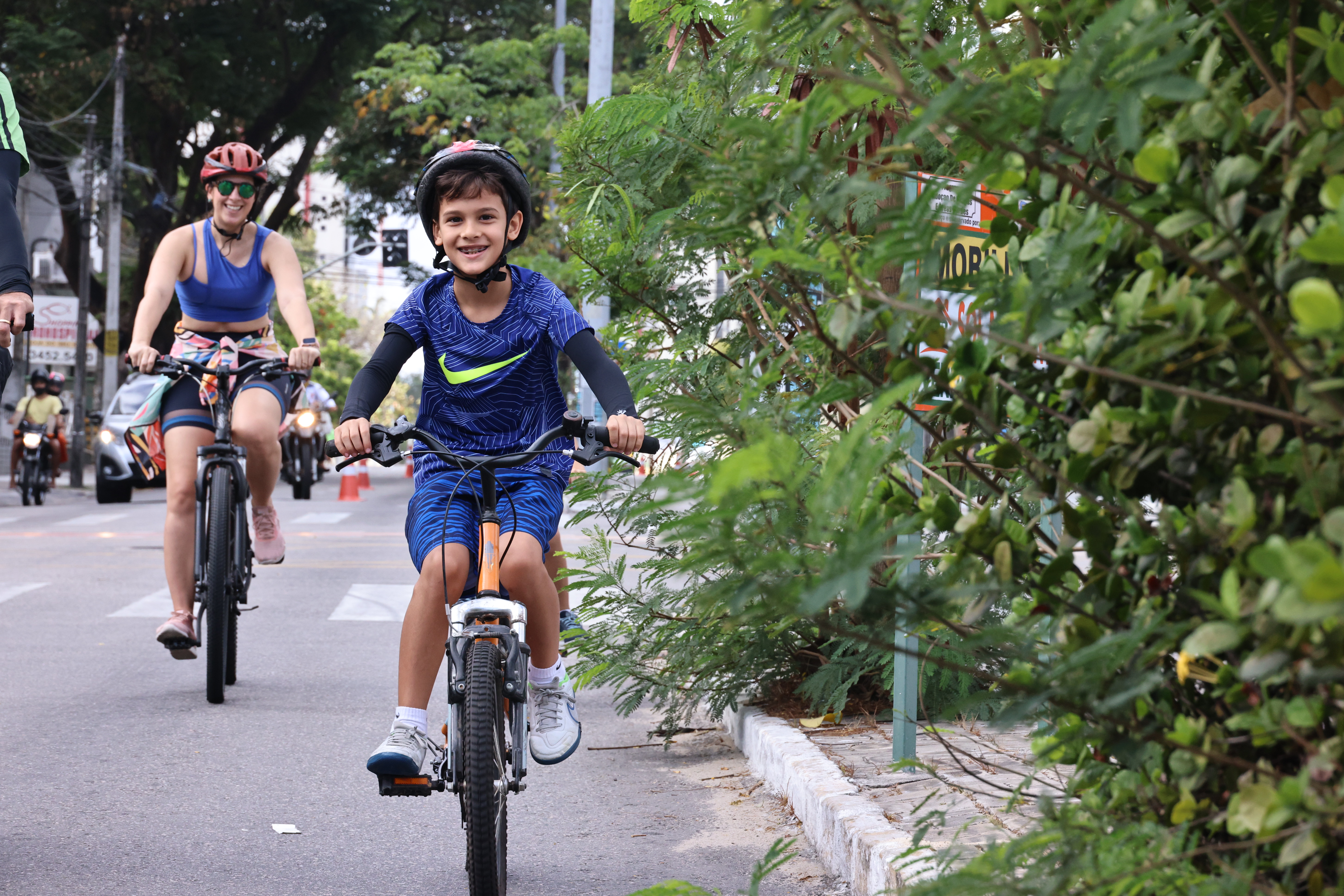 criança pedalando na ciclofaixa com a mãe