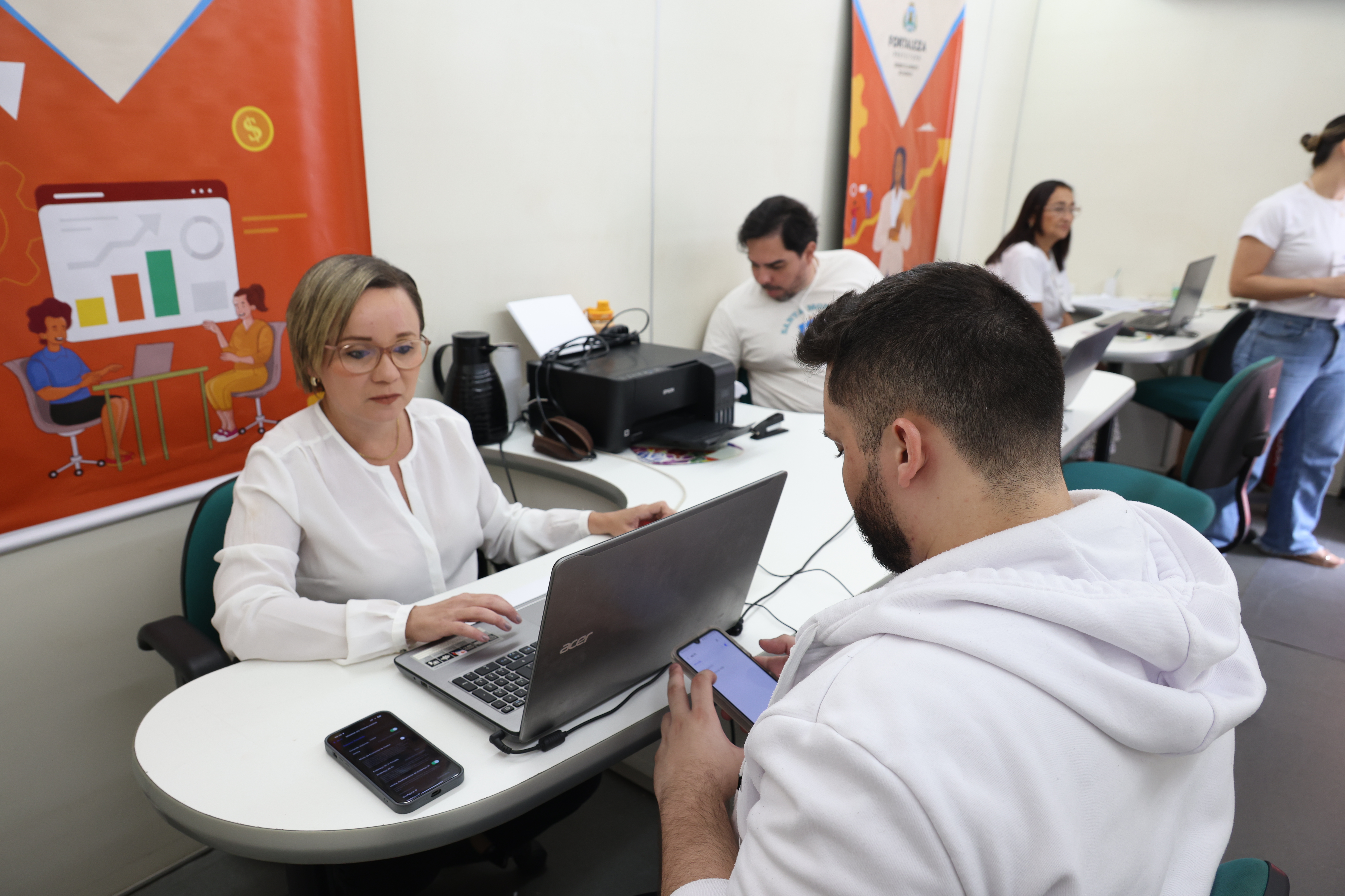 duas pessoas sentadas proximas ao computador